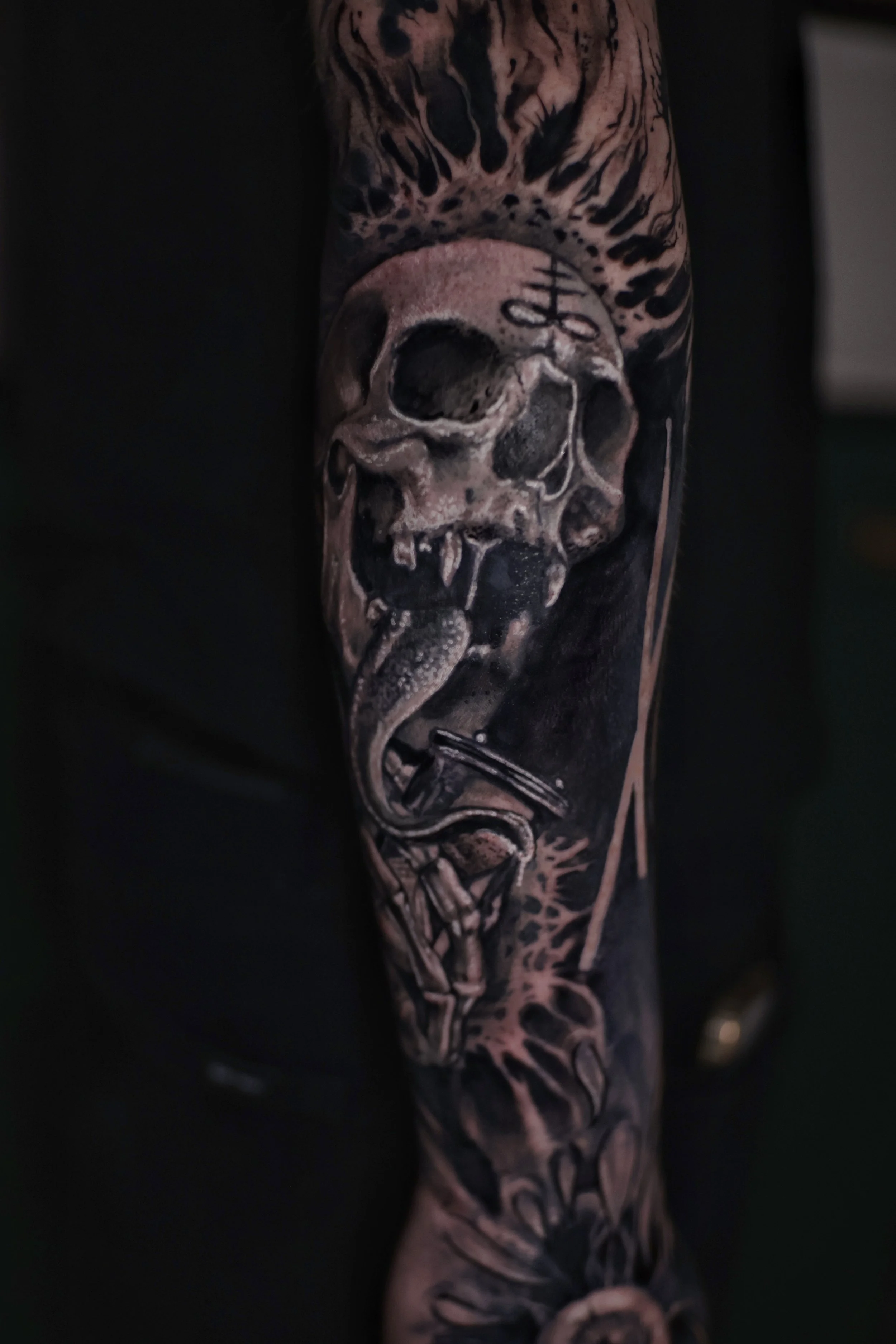Close-up of a person's arm with a tattoo of a skull and tiger face, featuring detailed shading and contrast.