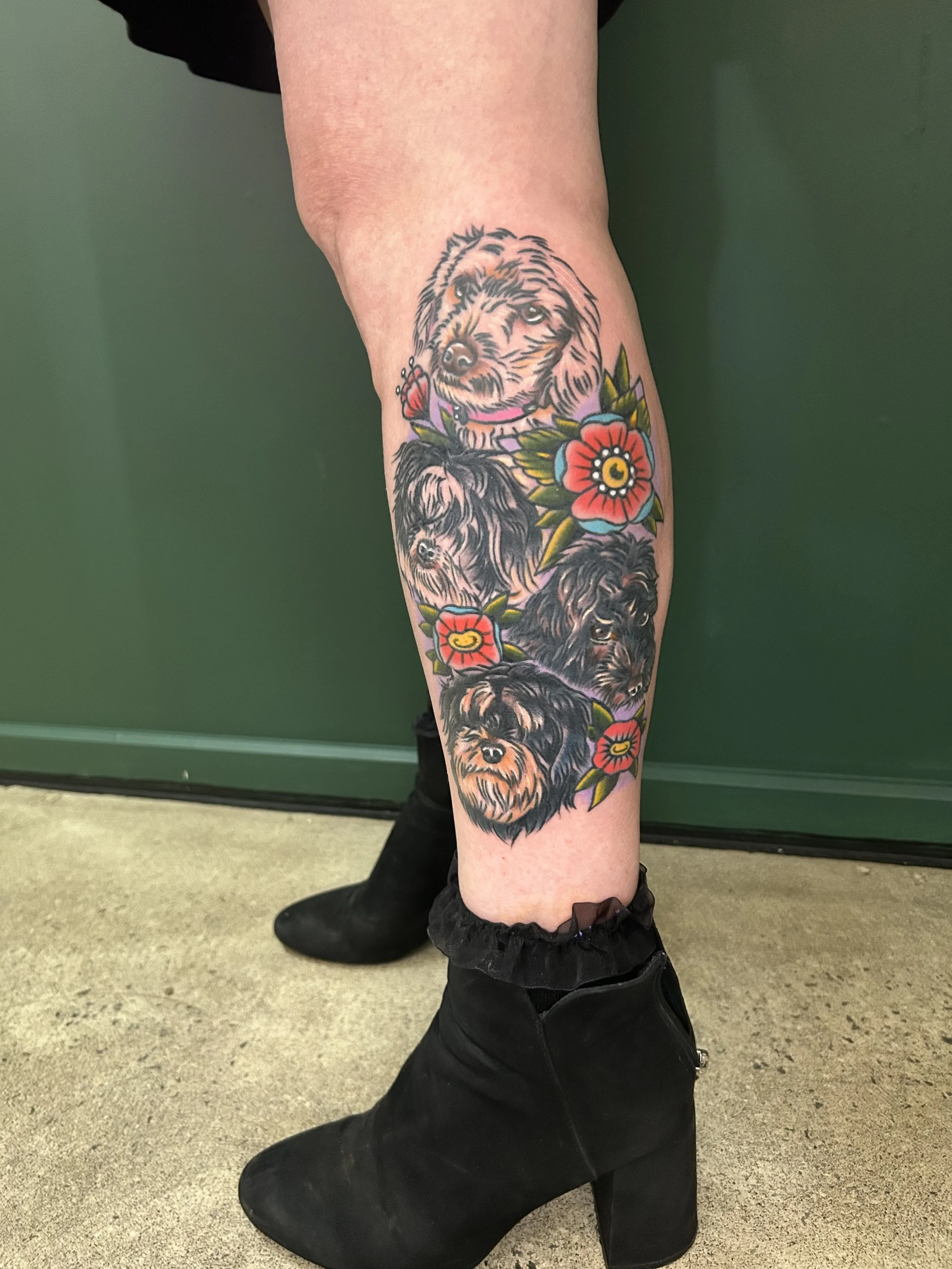 Tattoo of fluffy dogs with colorful flowers on a person's leg