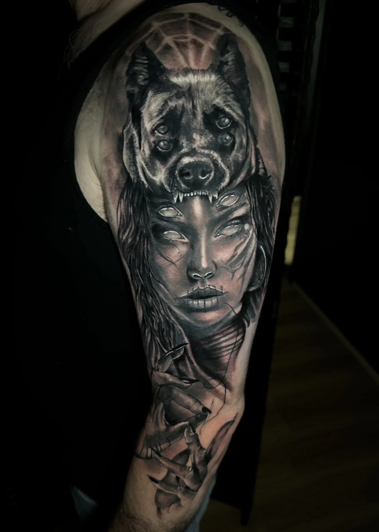 Tattoo of a woman with wolf face above her forehead and four eyes on her face, holding a needle