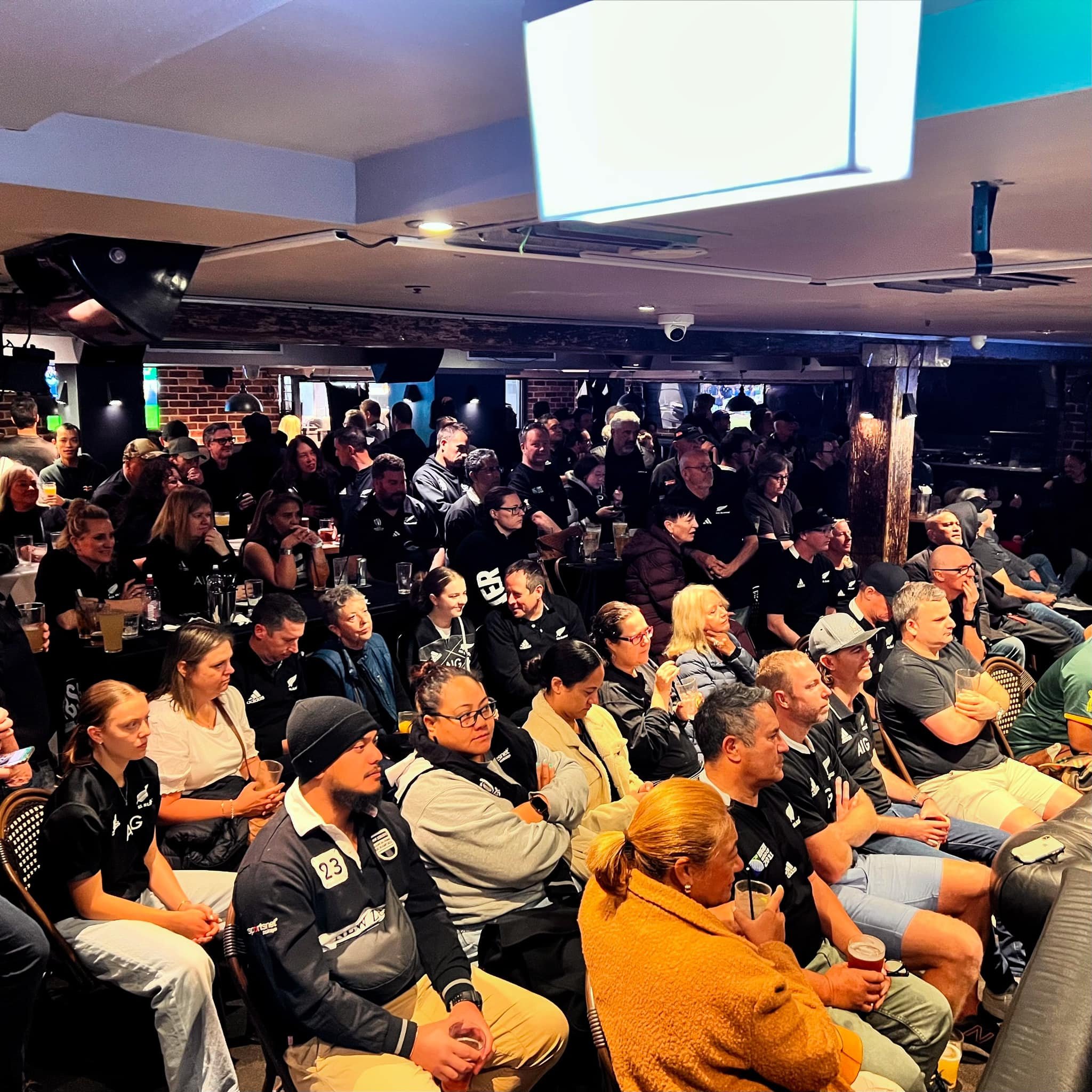 Night view of Cheers bar and restaurant exterior with illuminated signage, outdoor seating, and heaters.