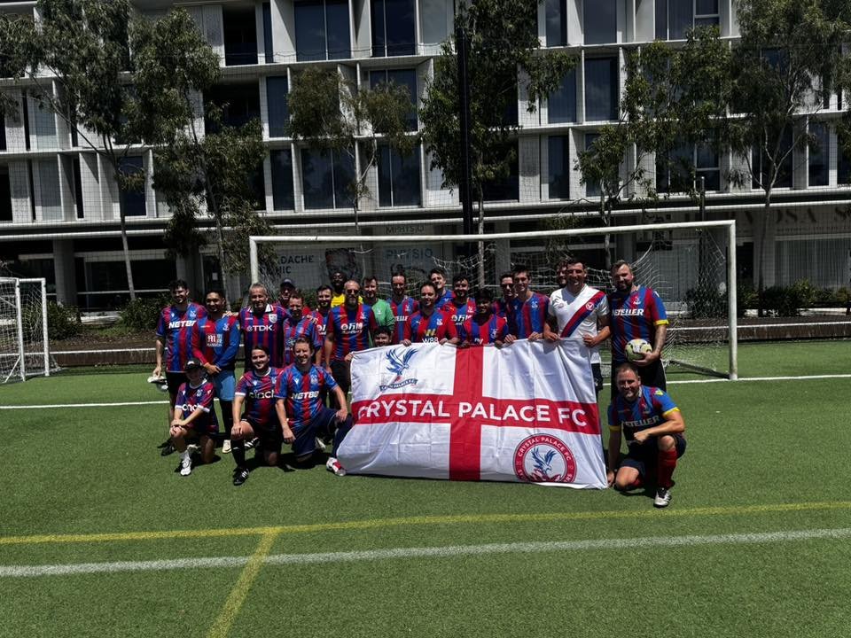 A soccer team holding a Crystal Palace FC flag on a soccer field.