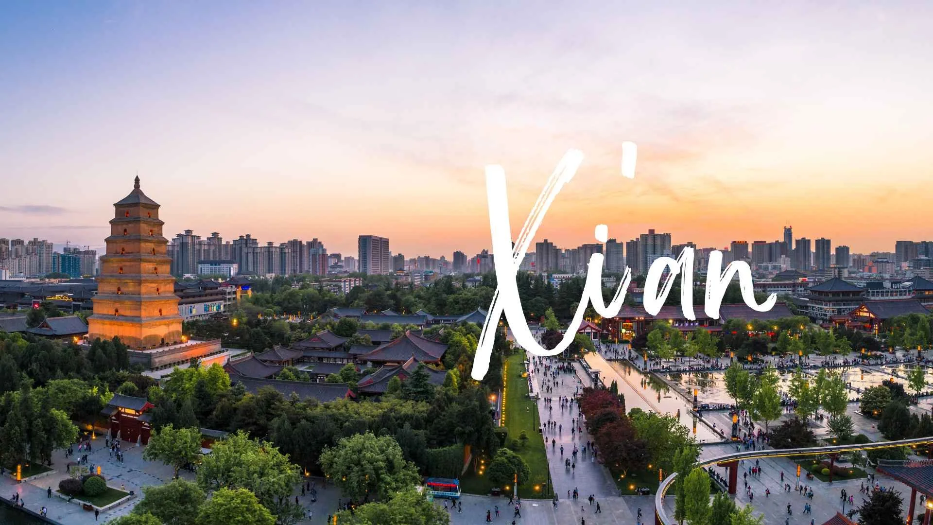 A cityscape at sunset featuring a traditional multi-tiered pagoda, modern high-rise buildings, and a busy park with many people walking and trees, with the word 'Xian' written across the sky.
