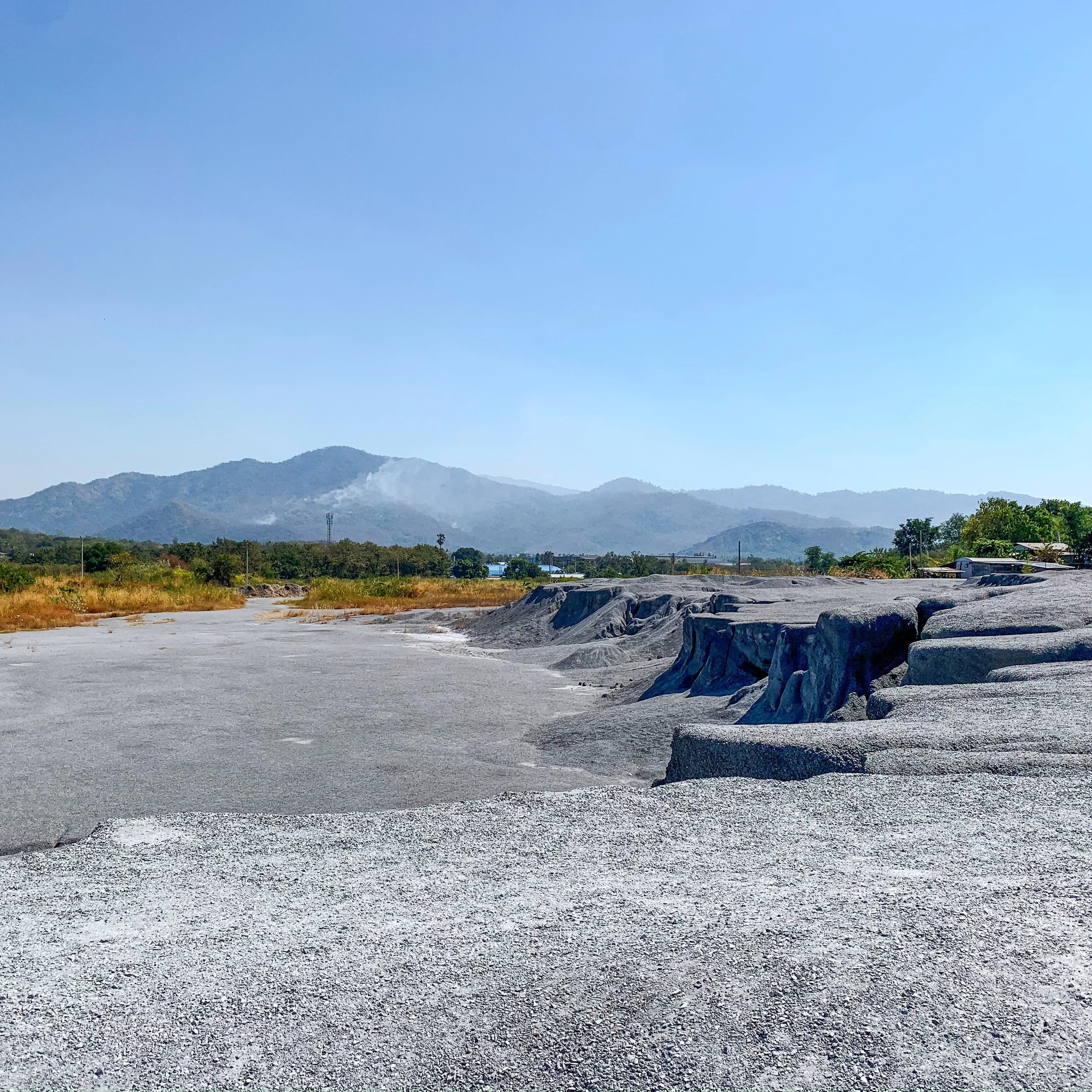Dry, rocky landscape with mountains in the background and a clear blue sky.