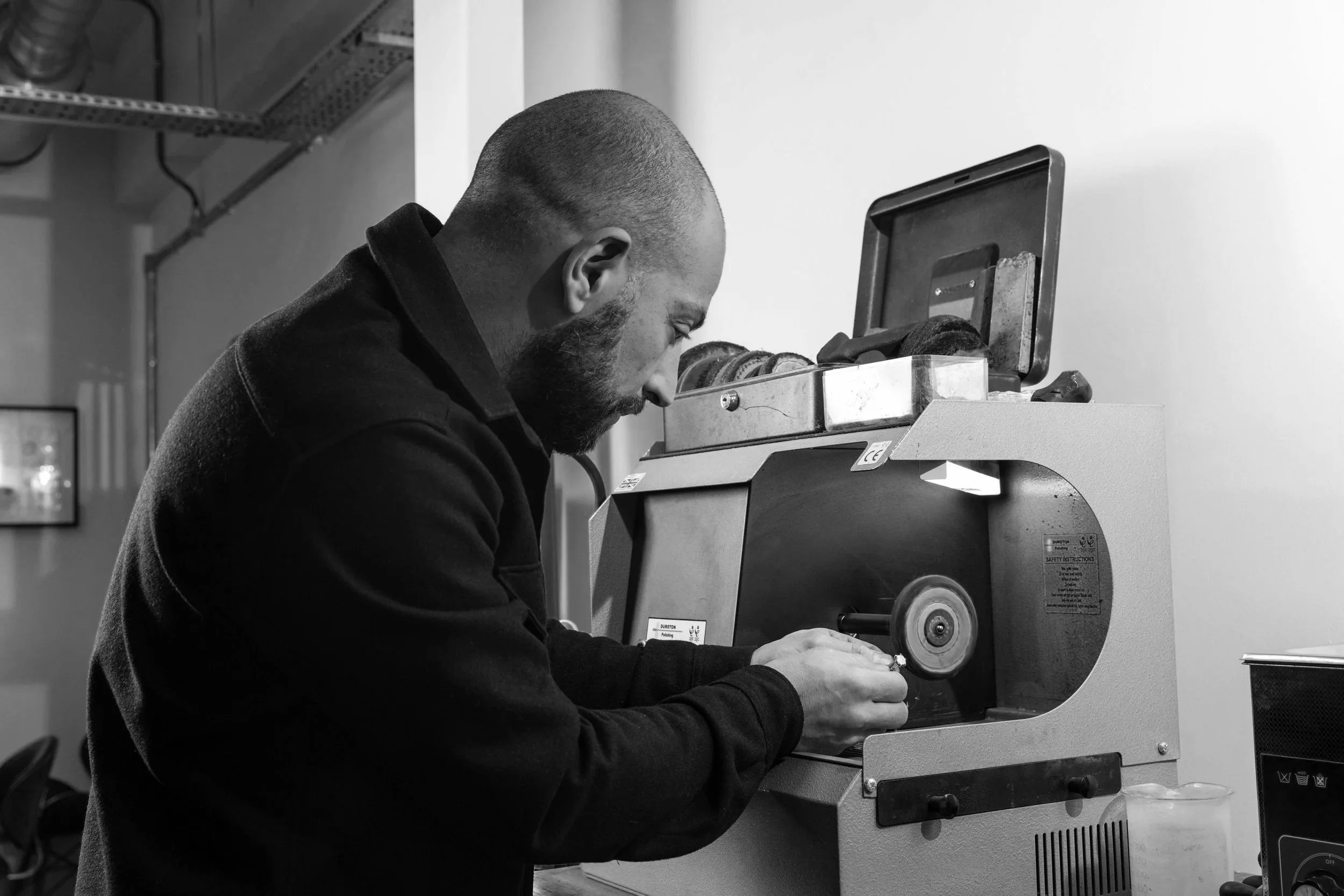 A man with a beard and bald head operating a shoe polishing machine, focused on polishing a shoe.