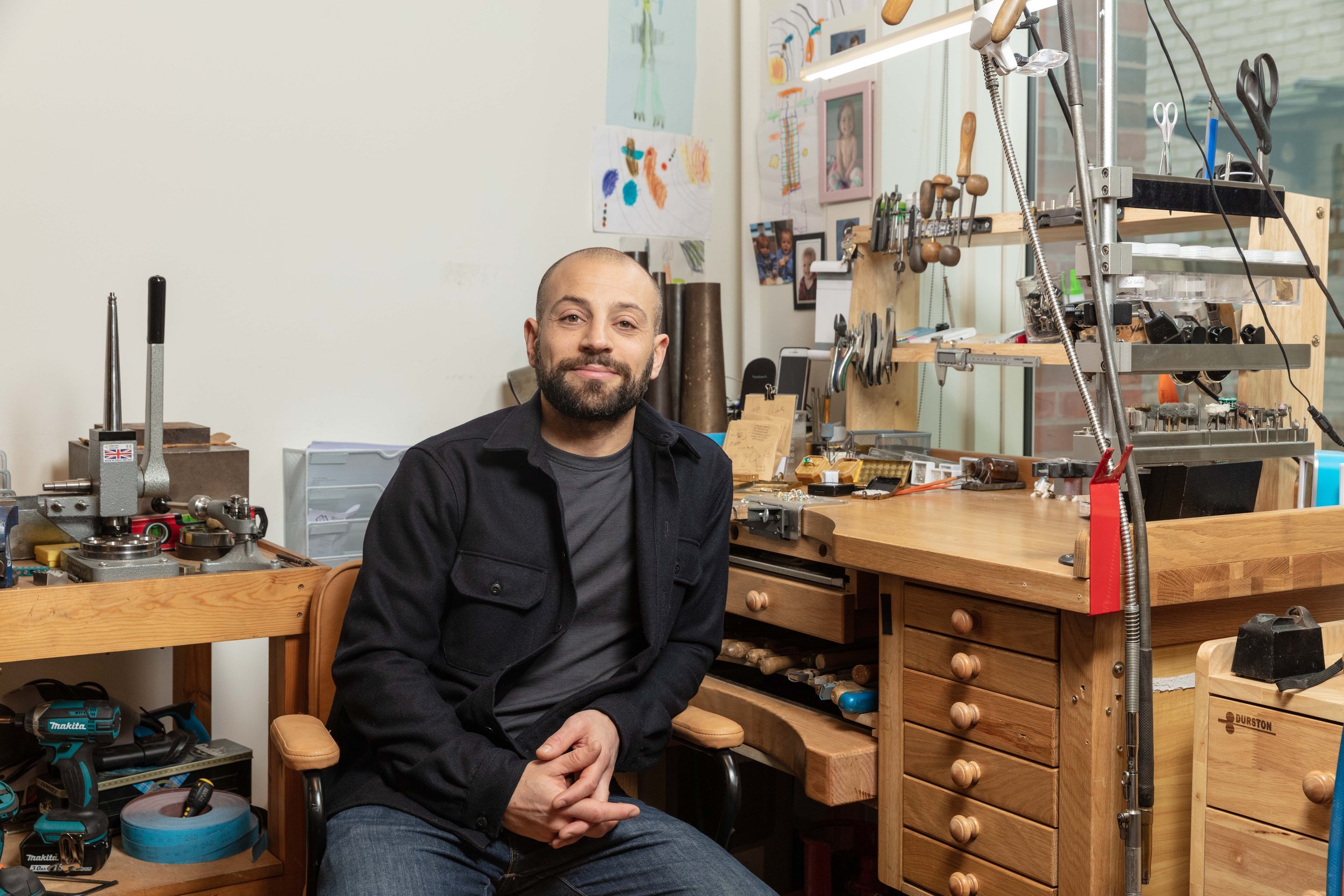 Daniel Greenberg, bespoke jeweller, smiling at his workbench in his Hatton Garden workshop, London