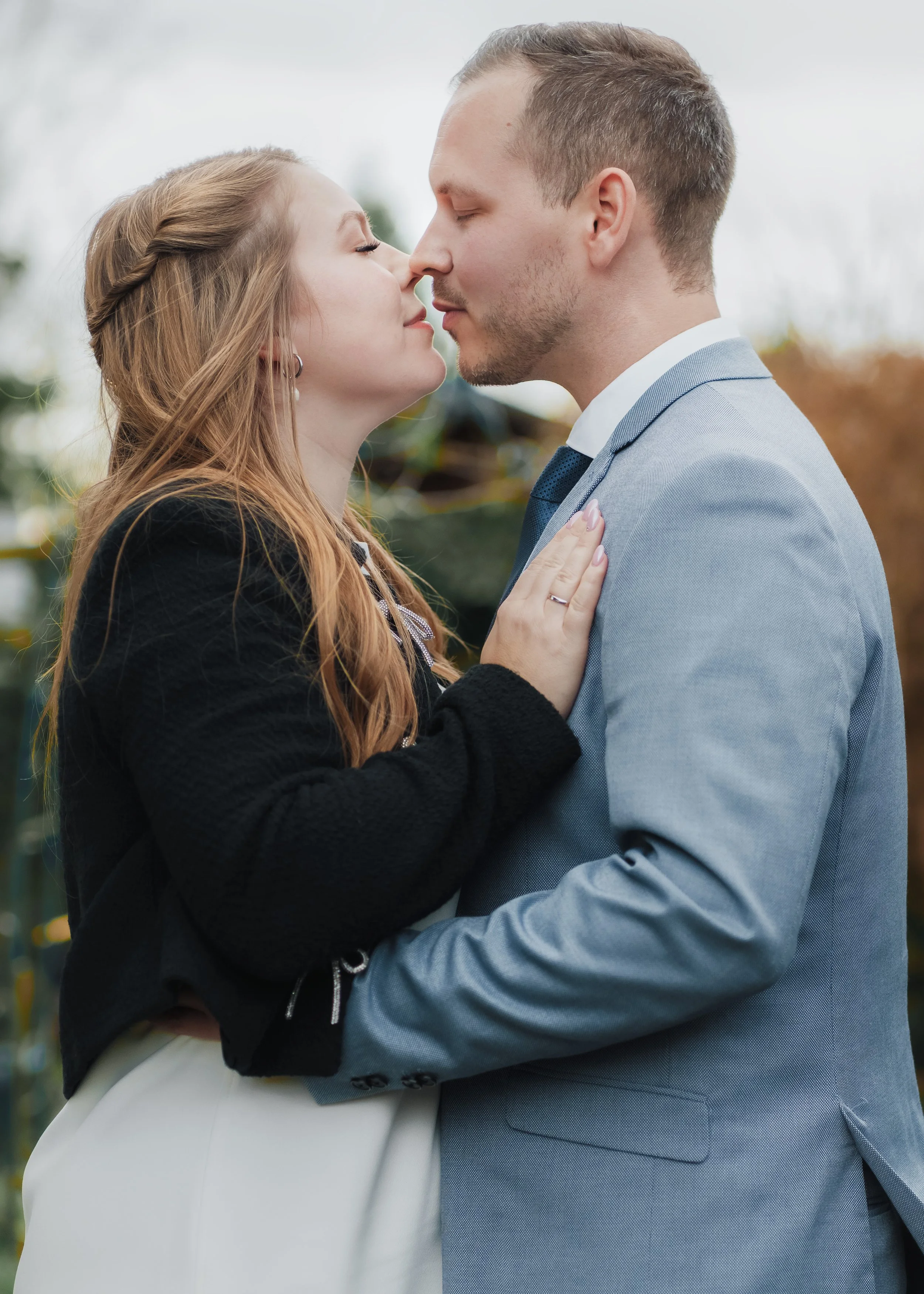 Ein Mann und eine Frau stehen sich sehr nahe, fast berührend, und scheinen sich tief in die Augen zu schauen, mit einer romantischen Atmosphäre im Freien.