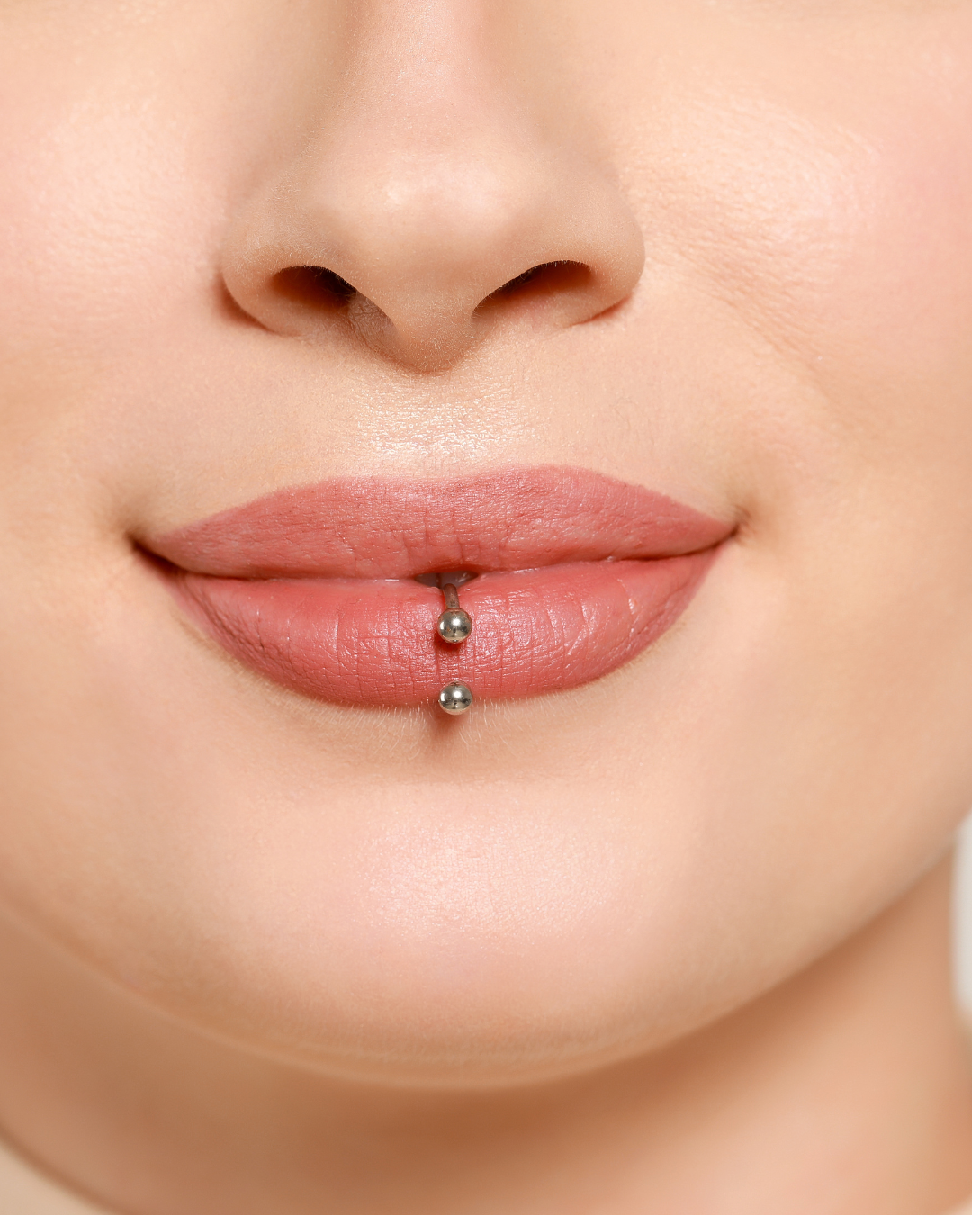 Close-up of a woman's lips with a barbell lip piercing.