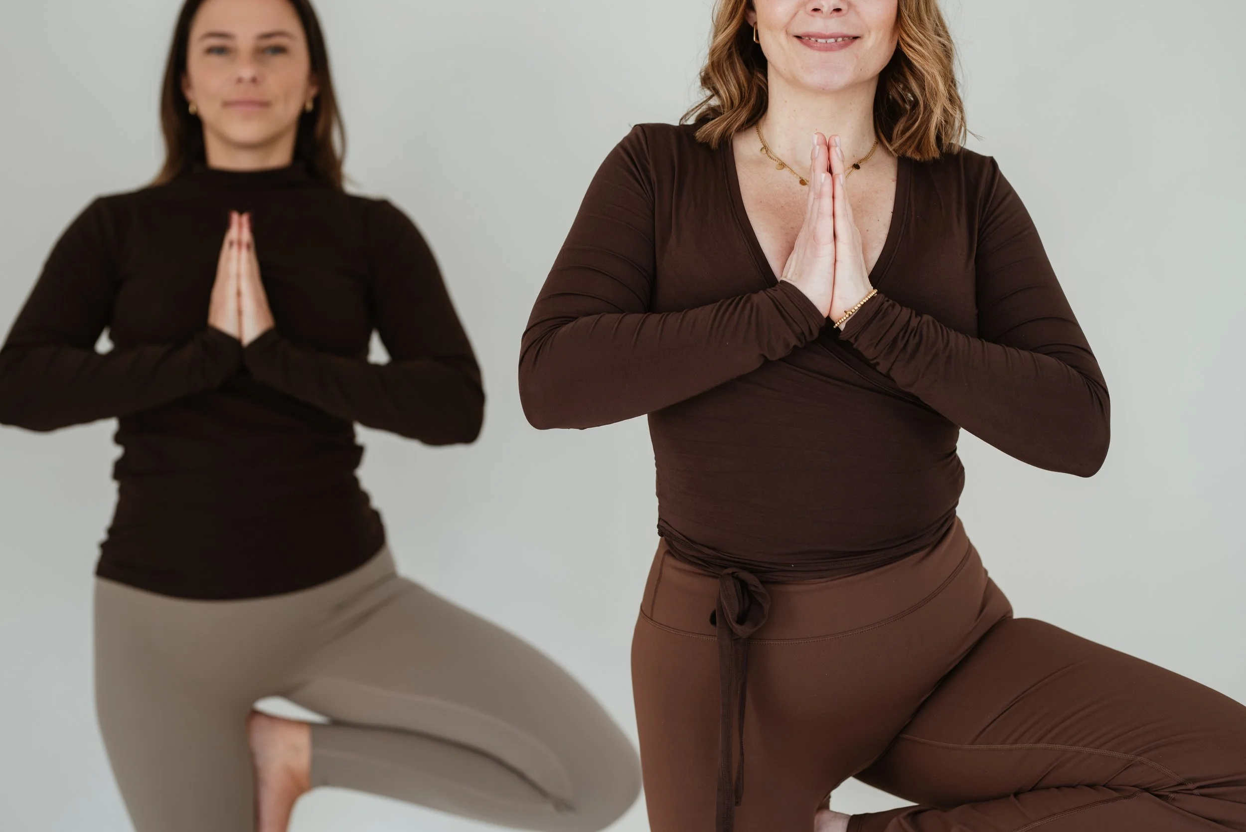 Zwei Frauen in Yoga-Pose, rechte Frau zeigt Yoga-Geste, linke Frau im Halbmond.