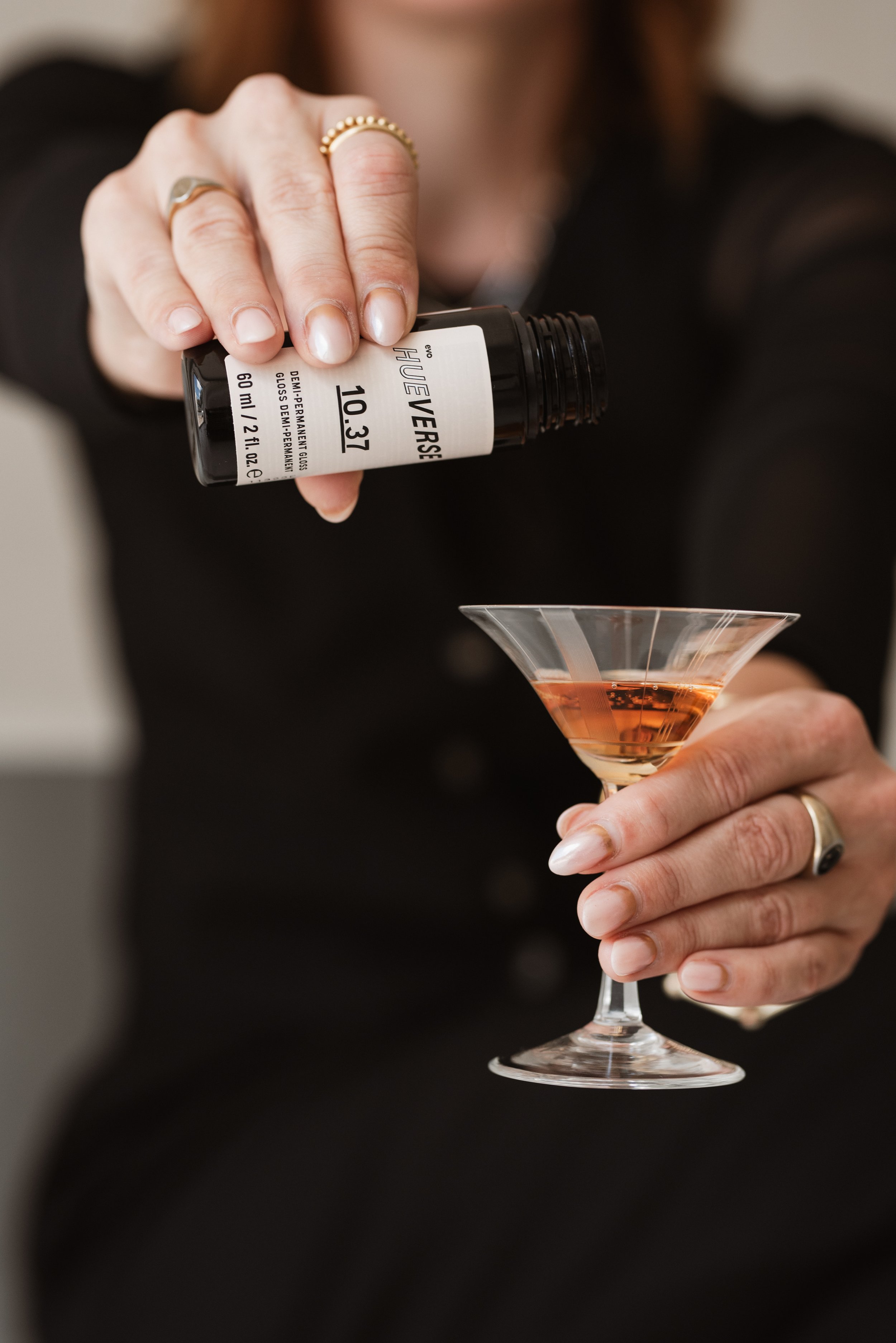 Nahaufnahme einer Person, die einen roten Likör in ein Cocktailglas gießt.