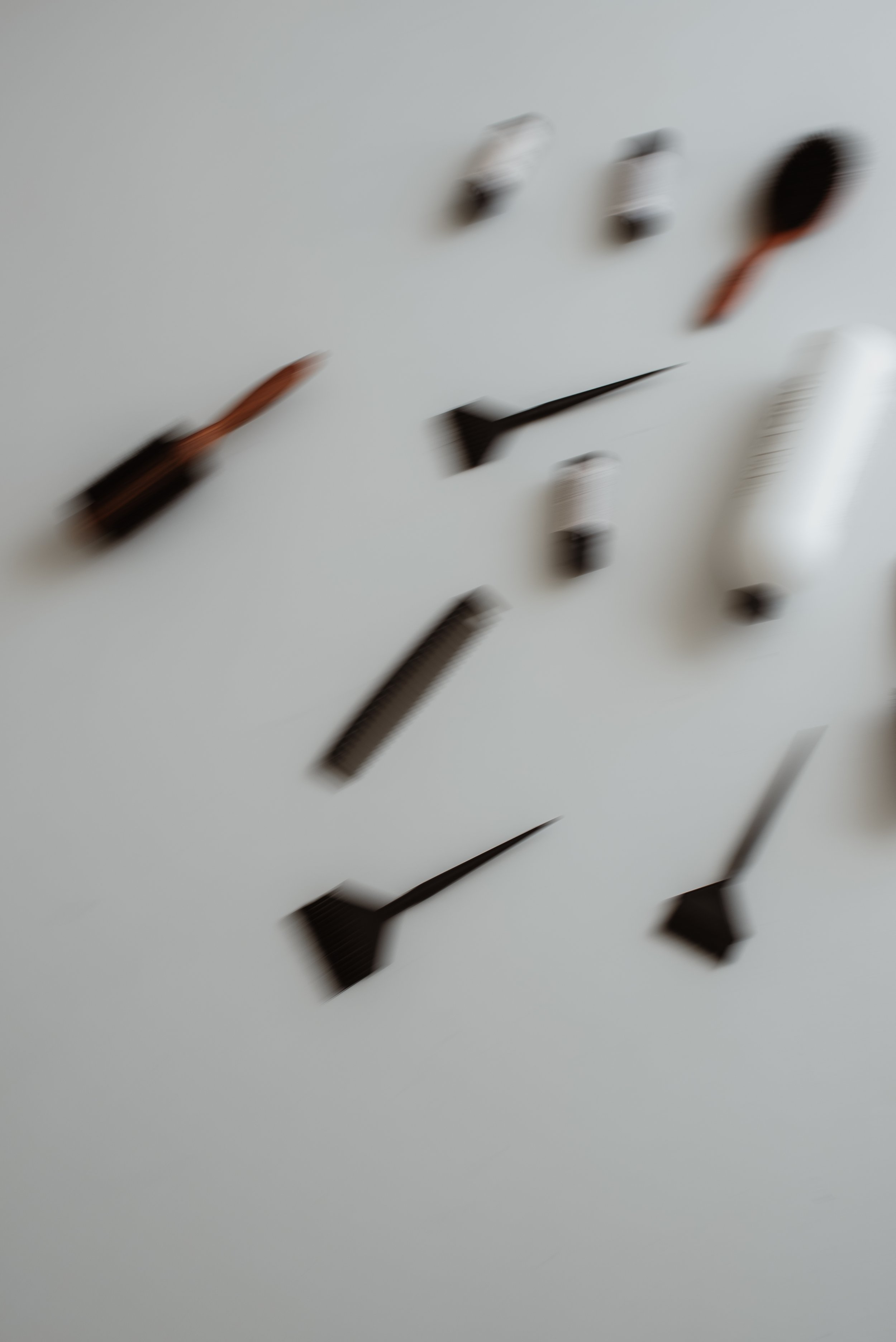 Nahaufnahme eines weißen Wanduhres mit schwarzen Zeigern, die nach oben und links zeigen, die Zeiger sind verschwommen durch Bewegung.