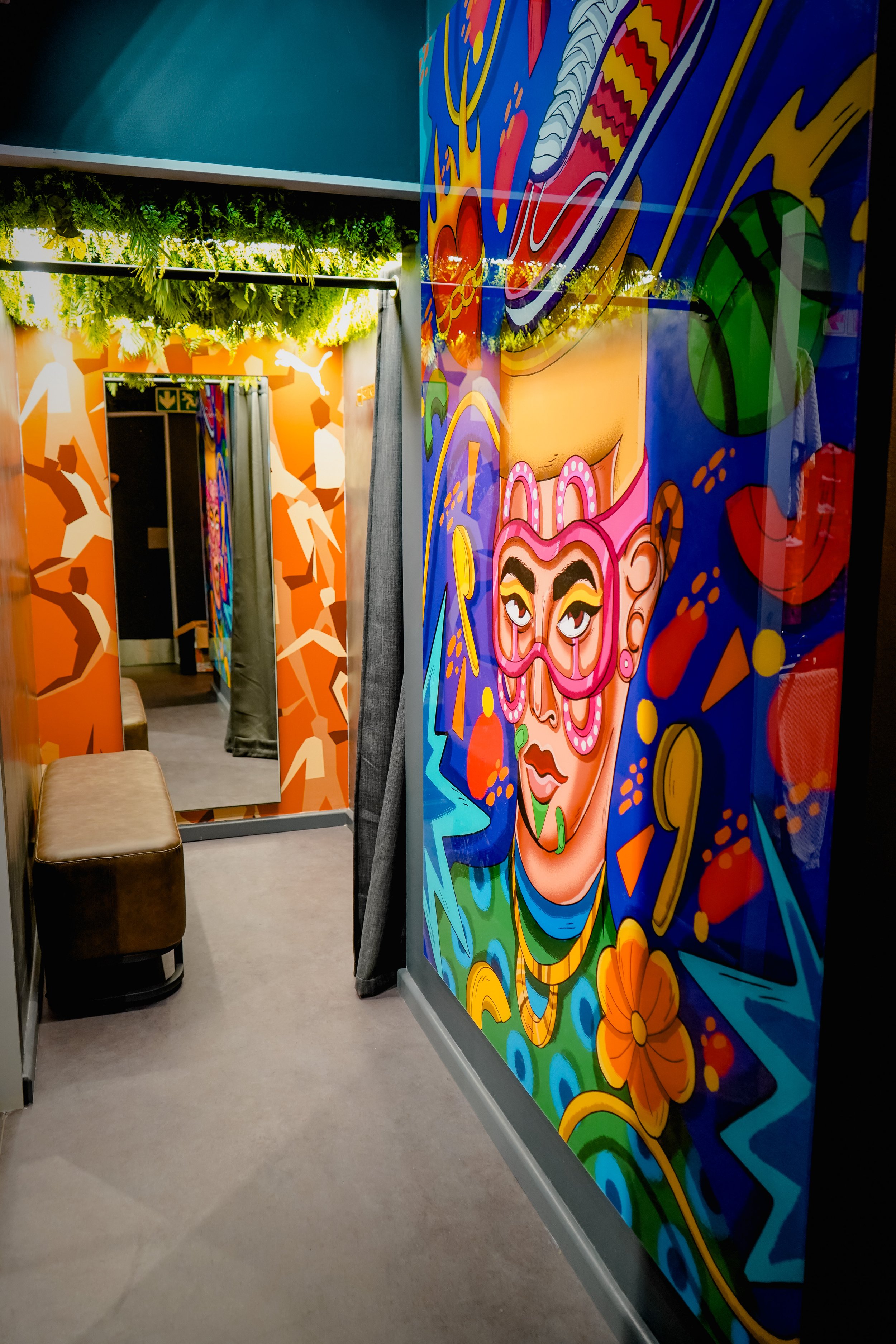 Colorful mural featuring a stylized female face with vibrant makeup, surrounded by abstract shapes and patterns.
