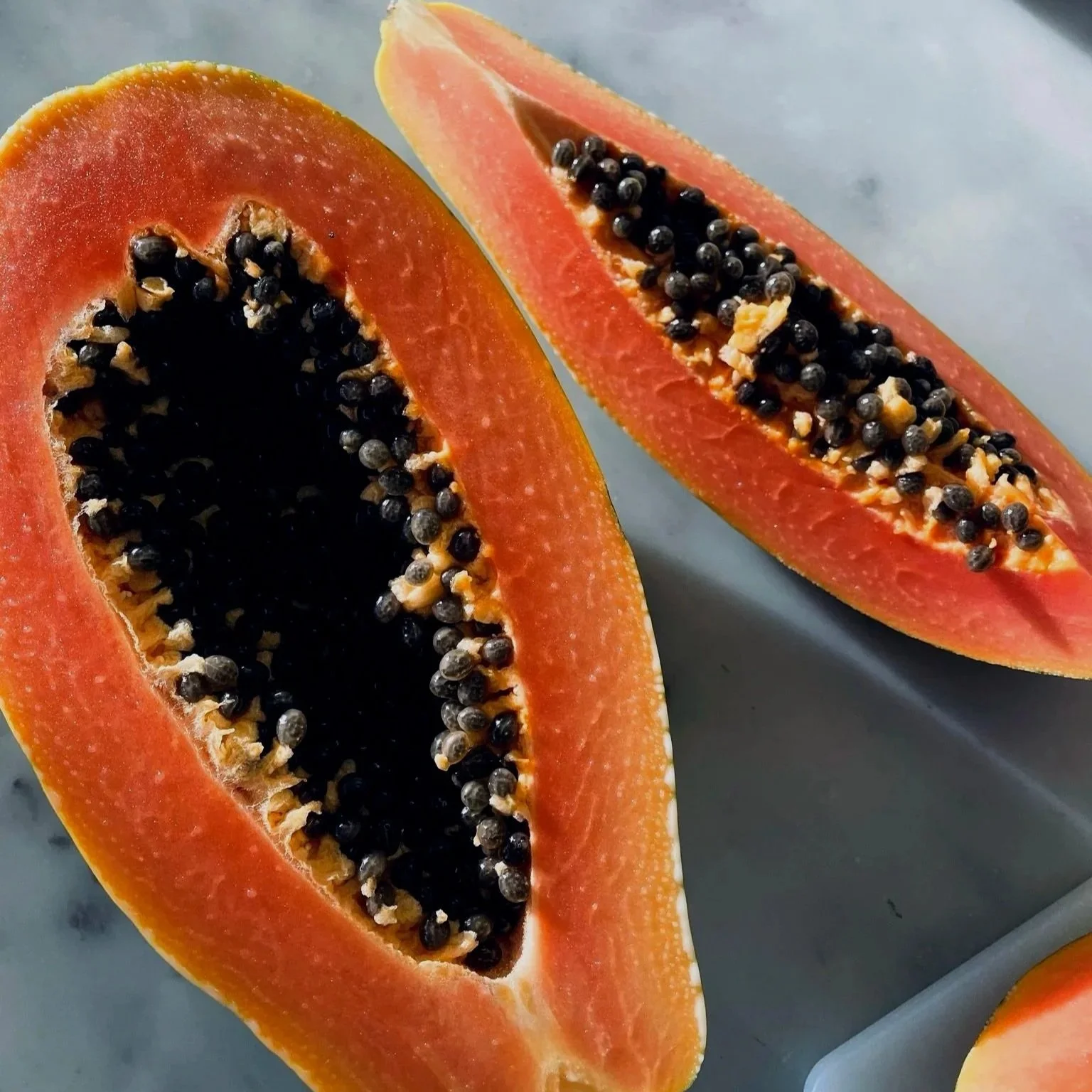 A sliced papaya showing orange flesh and black seeds