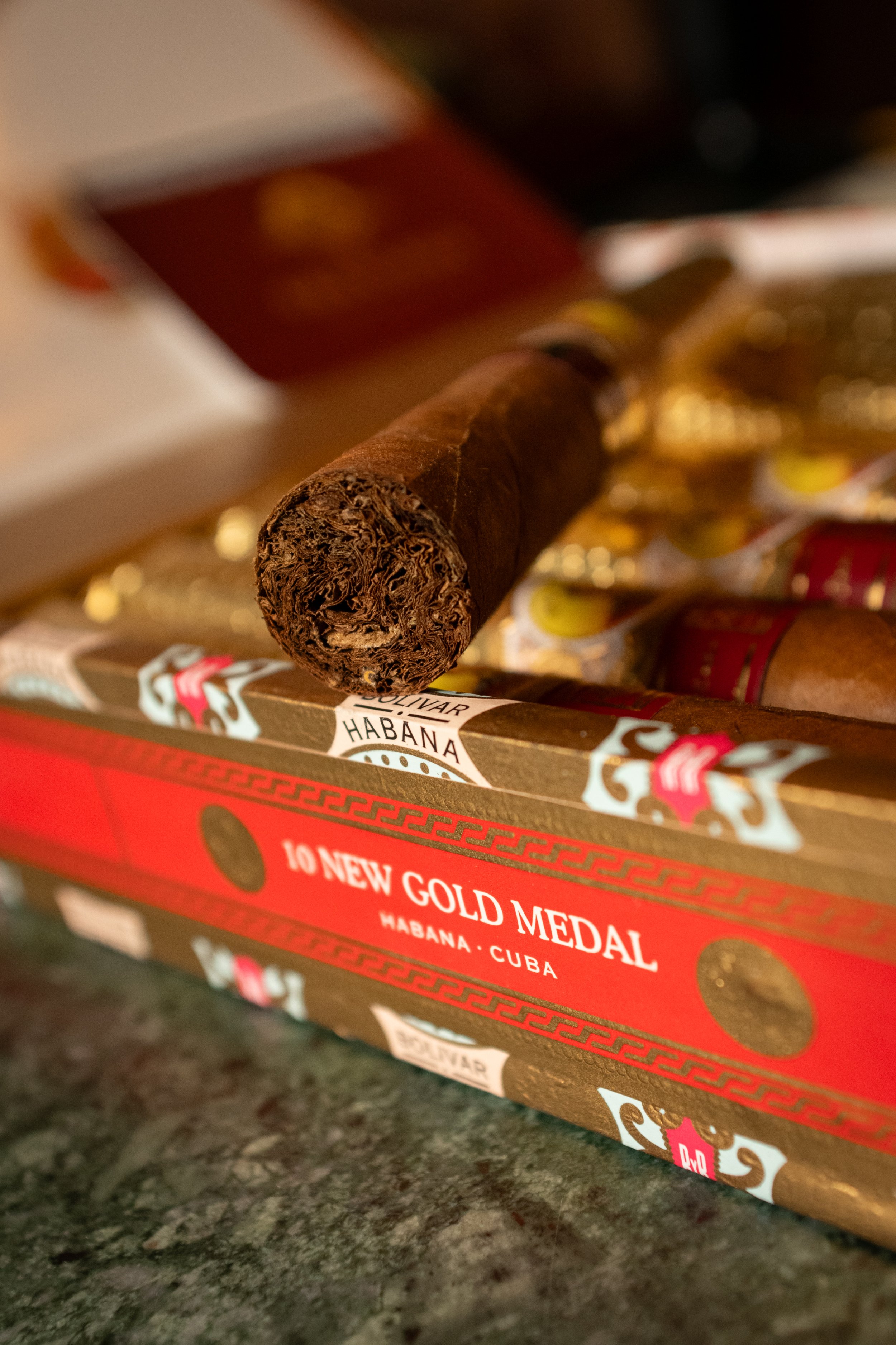 Un cigarro con su envoltura y una caja que dice '10 New Gold Medal, Habana, Cuba'.