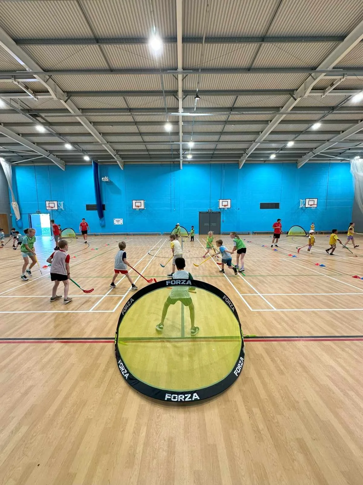 Children playing indoor hockey during a MegaCamps holiday club session by First Touch Sports in Buckinghamshire