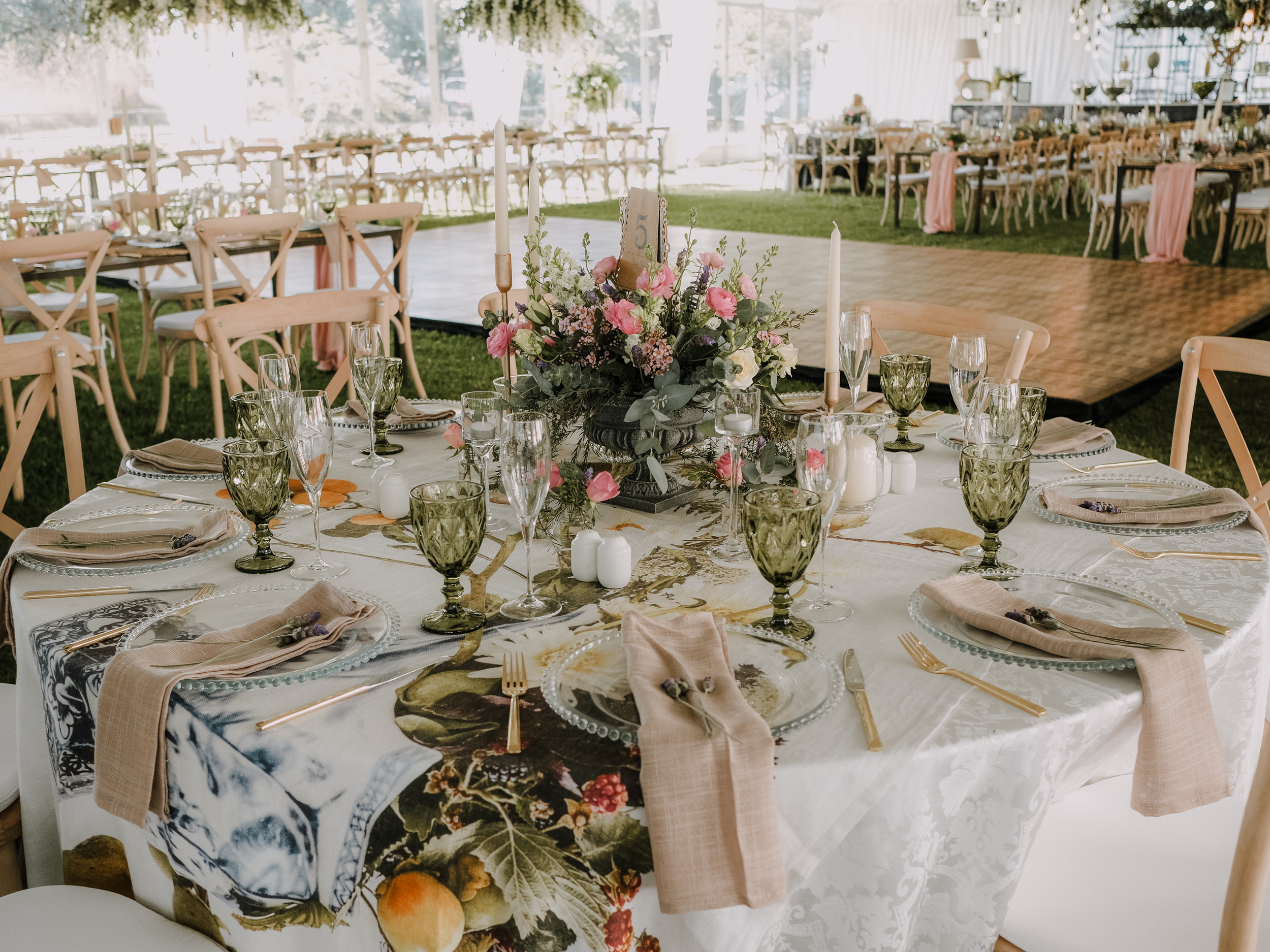 Elegant banquet table set with floral centerpiece, candles, glassware, plates, and napkins in a decorated event space.