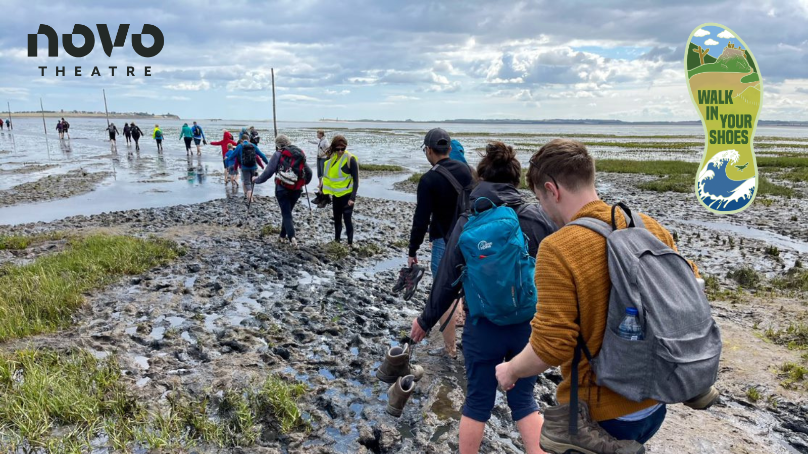 Group of people walking in a line across the causeway at Holy Island