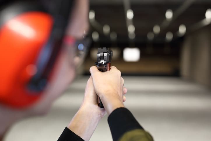 Person aiming a handgun at a target in a shooting range.
