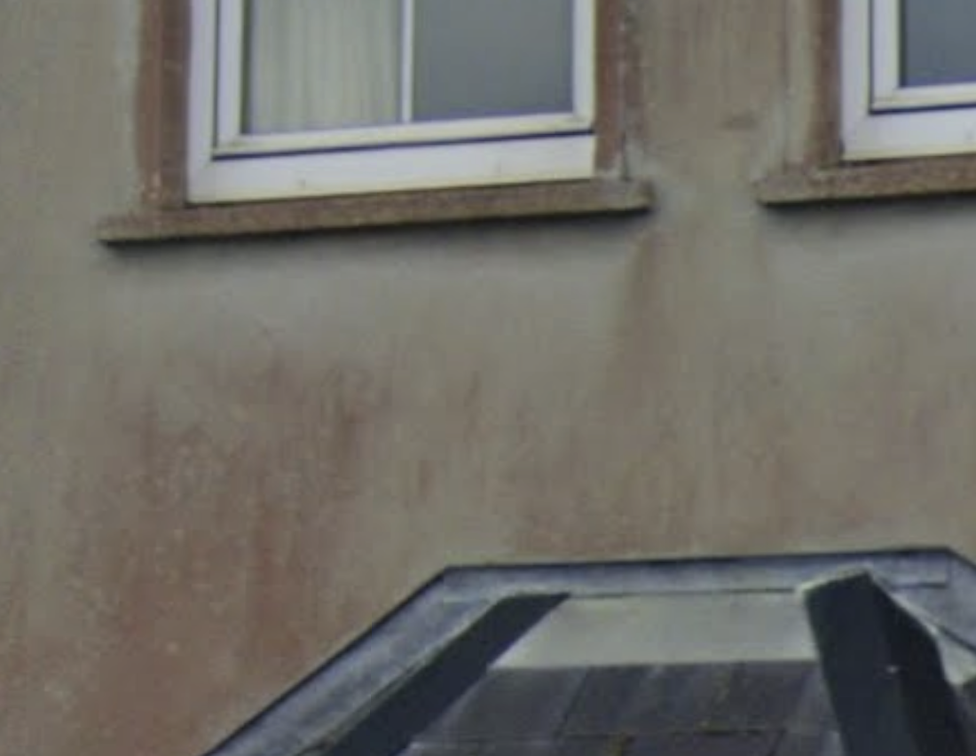Red and pink biological staining visible on an exterior rendered wall