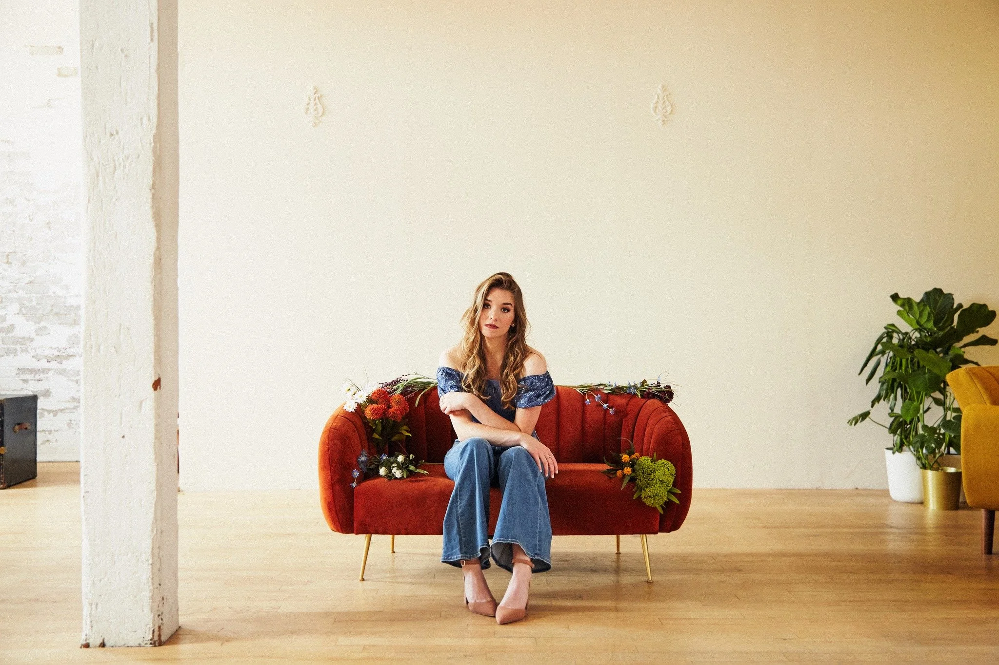 Steph La Rochelle seated on a red sofa during a promotional photoshoot
