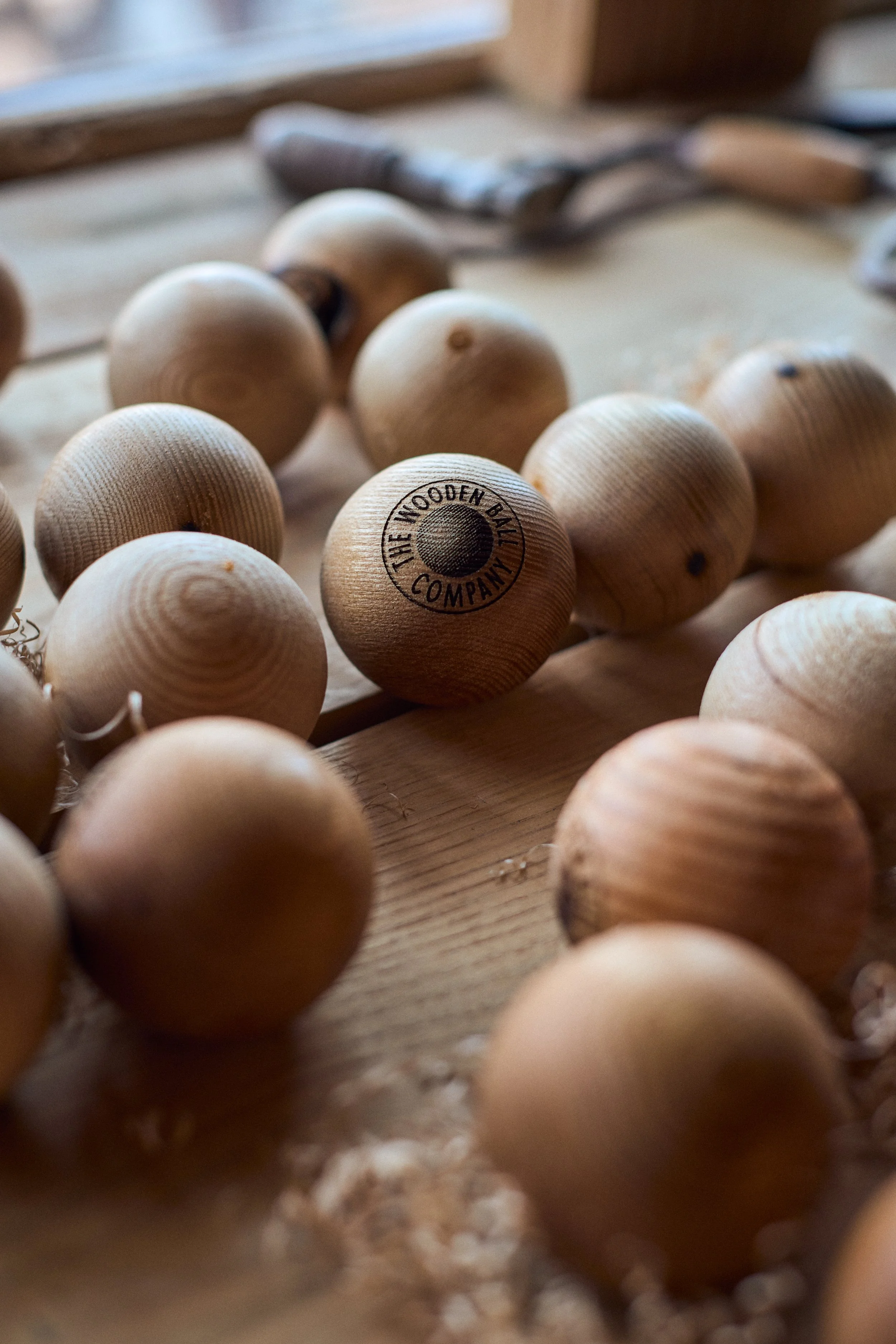 A collection of wooden ball toys on a wooden surface, with one ball marked "The Wooden Ball Company".
