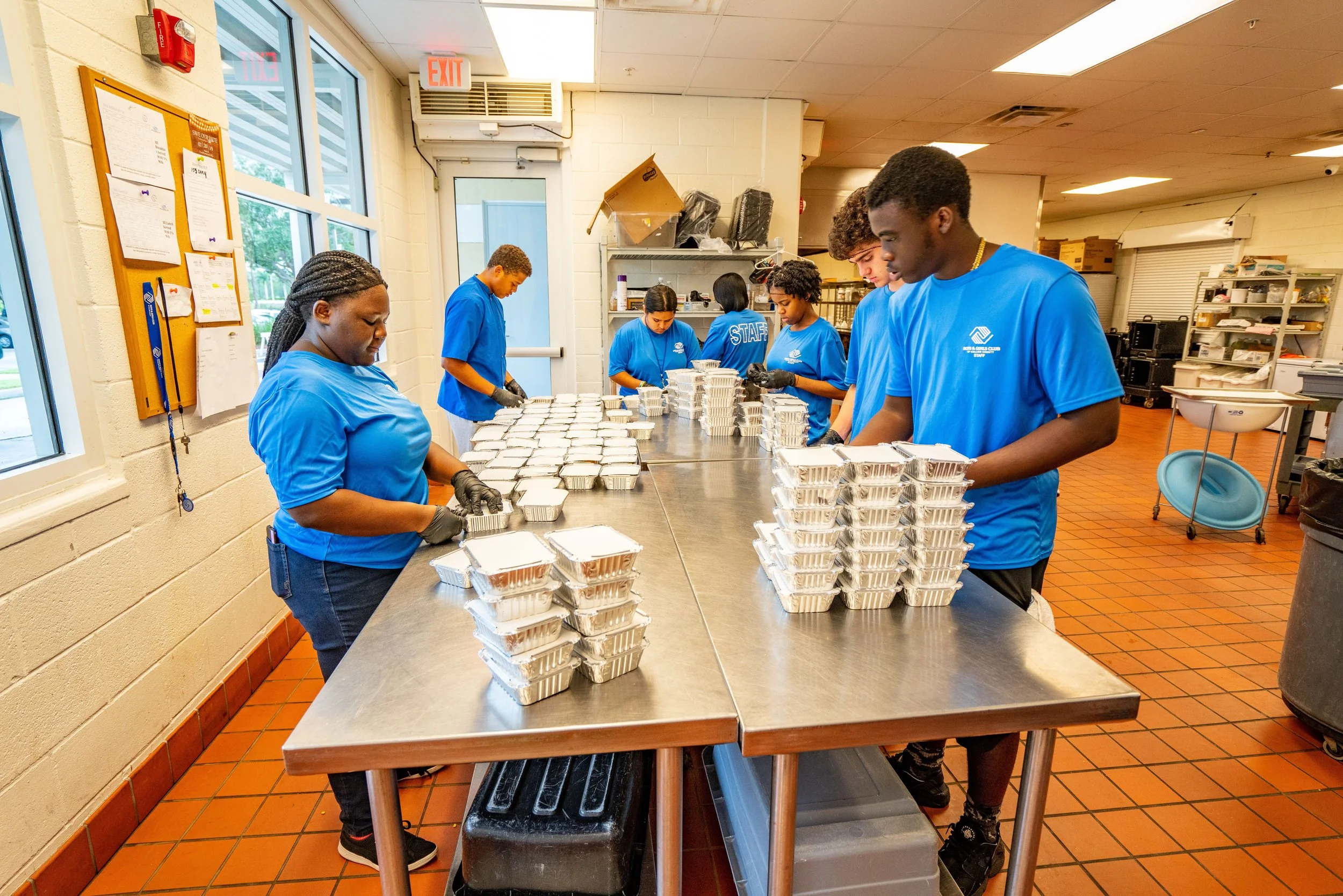 Group of volunteers packing food containers in a community kitchen.