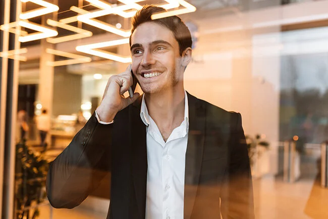 graphicstock-smiling-business-man-in-suit-talking-on-phone-behind-the-glass-and-looking-aside_SIWx6pv7Ohl-1.jpg