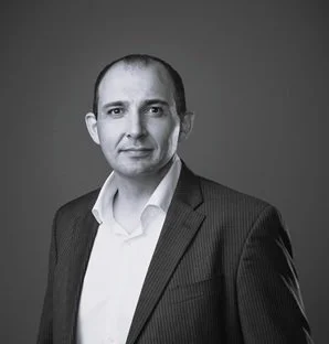 Black and white portrait of a man in a suit and white shirt looking at the camera.