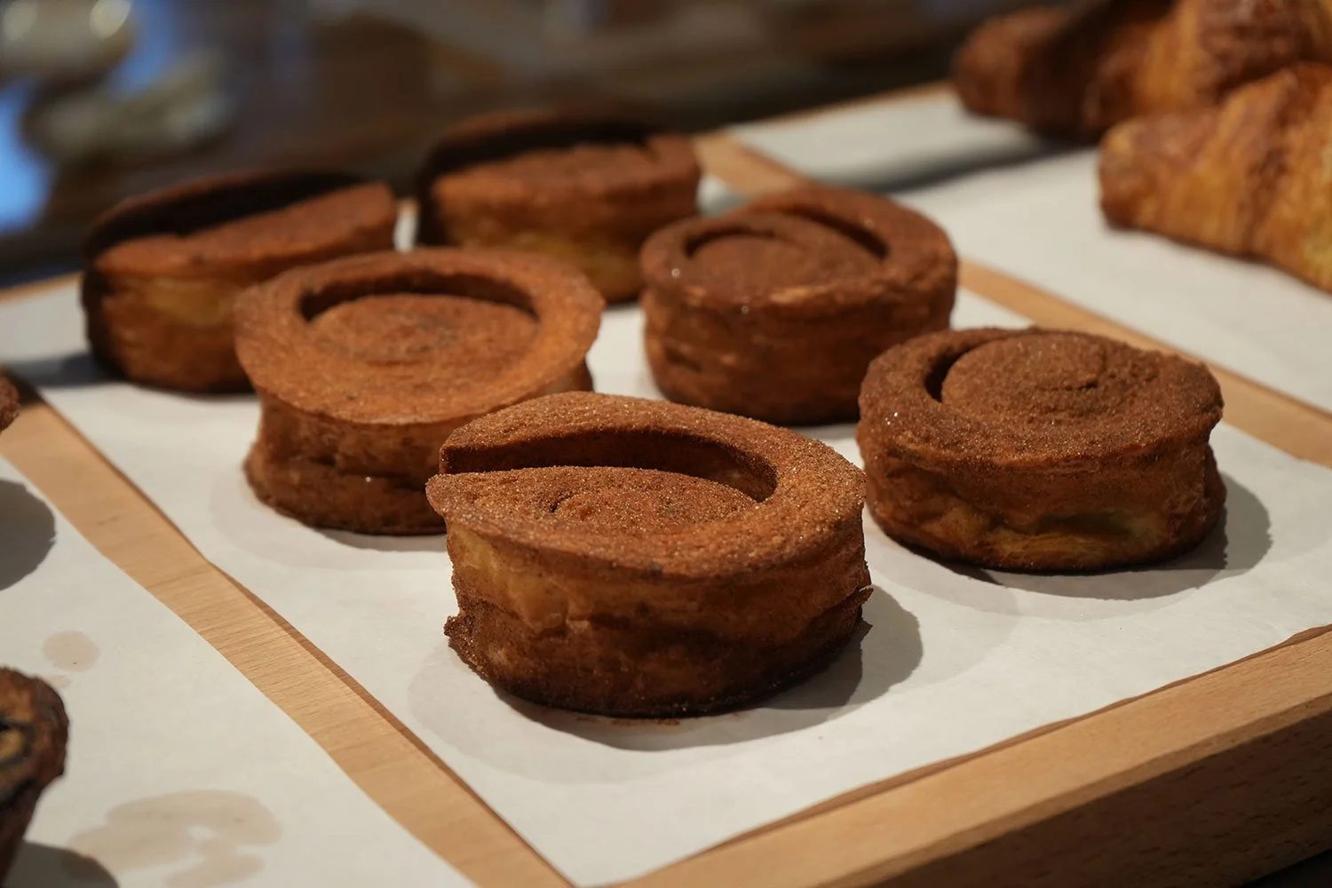 Close-up of cinnamon rolls on a wooden board with parchment paper.