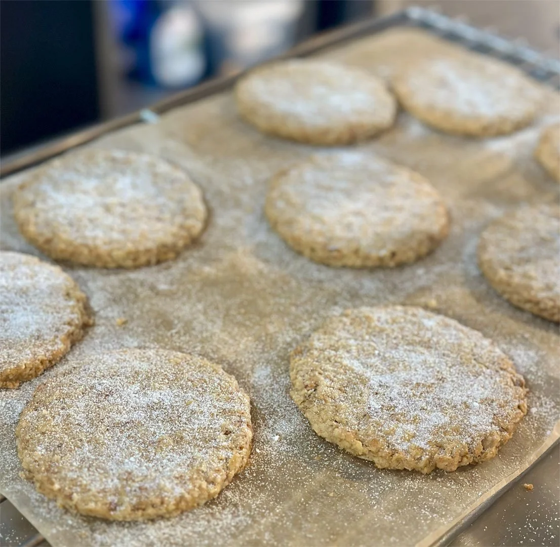 Freshly baked Irish oatmeal shortbread dusted with powdered sugar on a baking sheet.