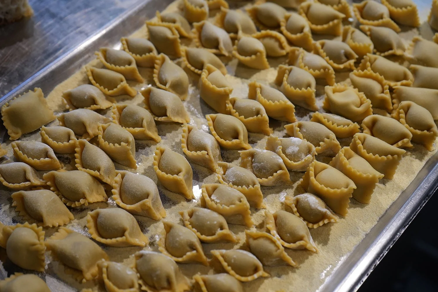 Unbaked pierogis on a baking sheet dusted with flour.