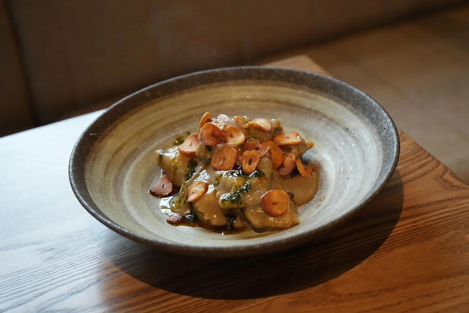 A bowl with a dish topped with sliced almonds, placed on a wooden surface.