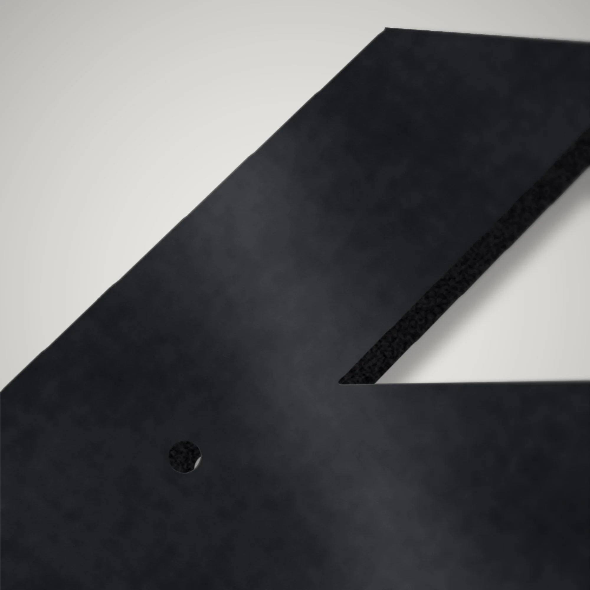 Close-up of a countersink-ready fixing hole and plasma-cut edge on a 4 mm steel numeral
