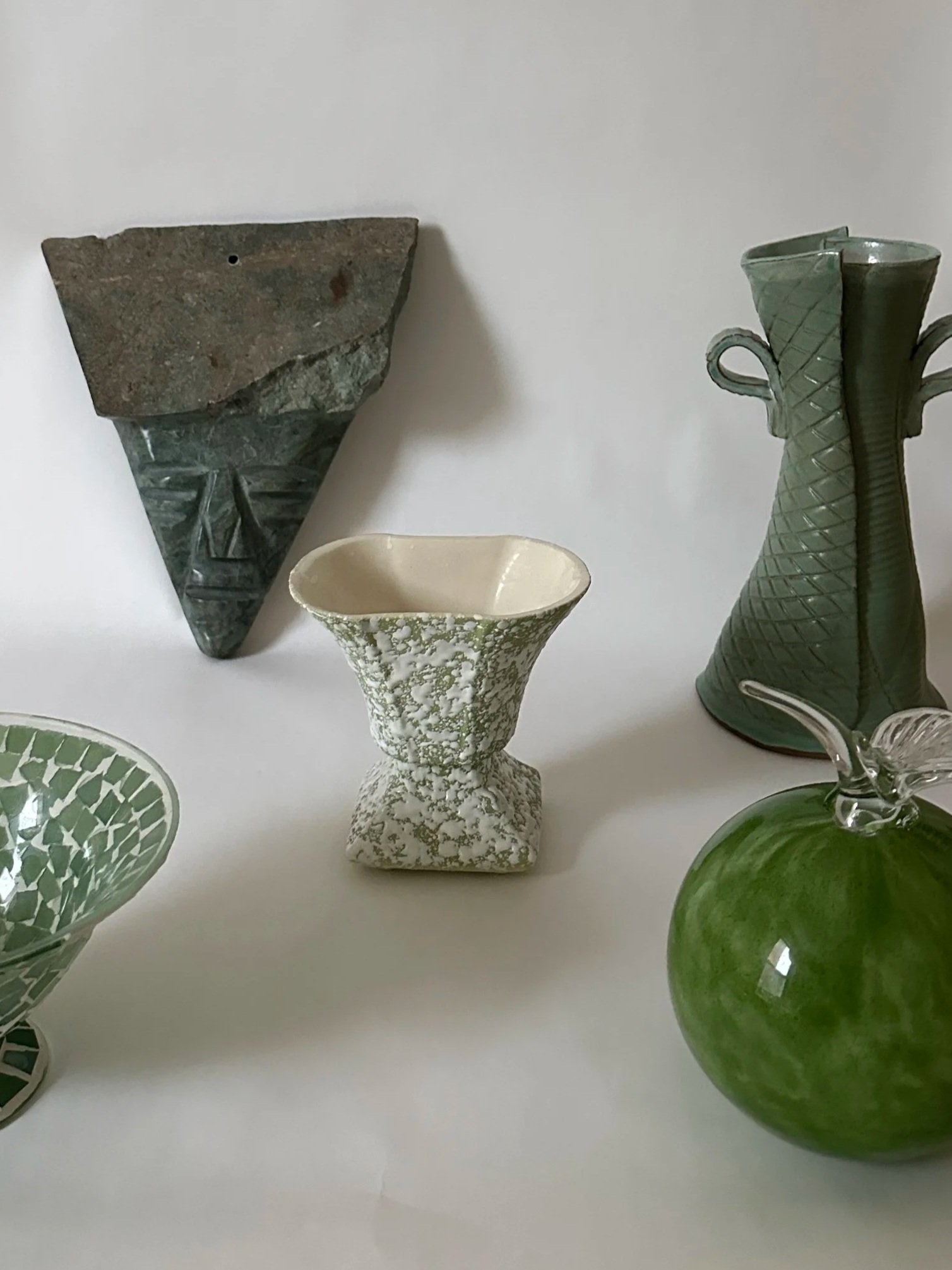 Set of colorful nested ceramic bowls in green, black, and orange on a white fabric background.