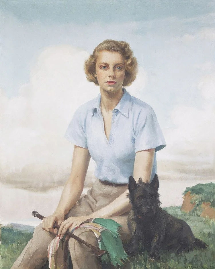 A woman with short blonde curly hair sitting outdoors on grass with a small black dog beside her, holding a rifle.