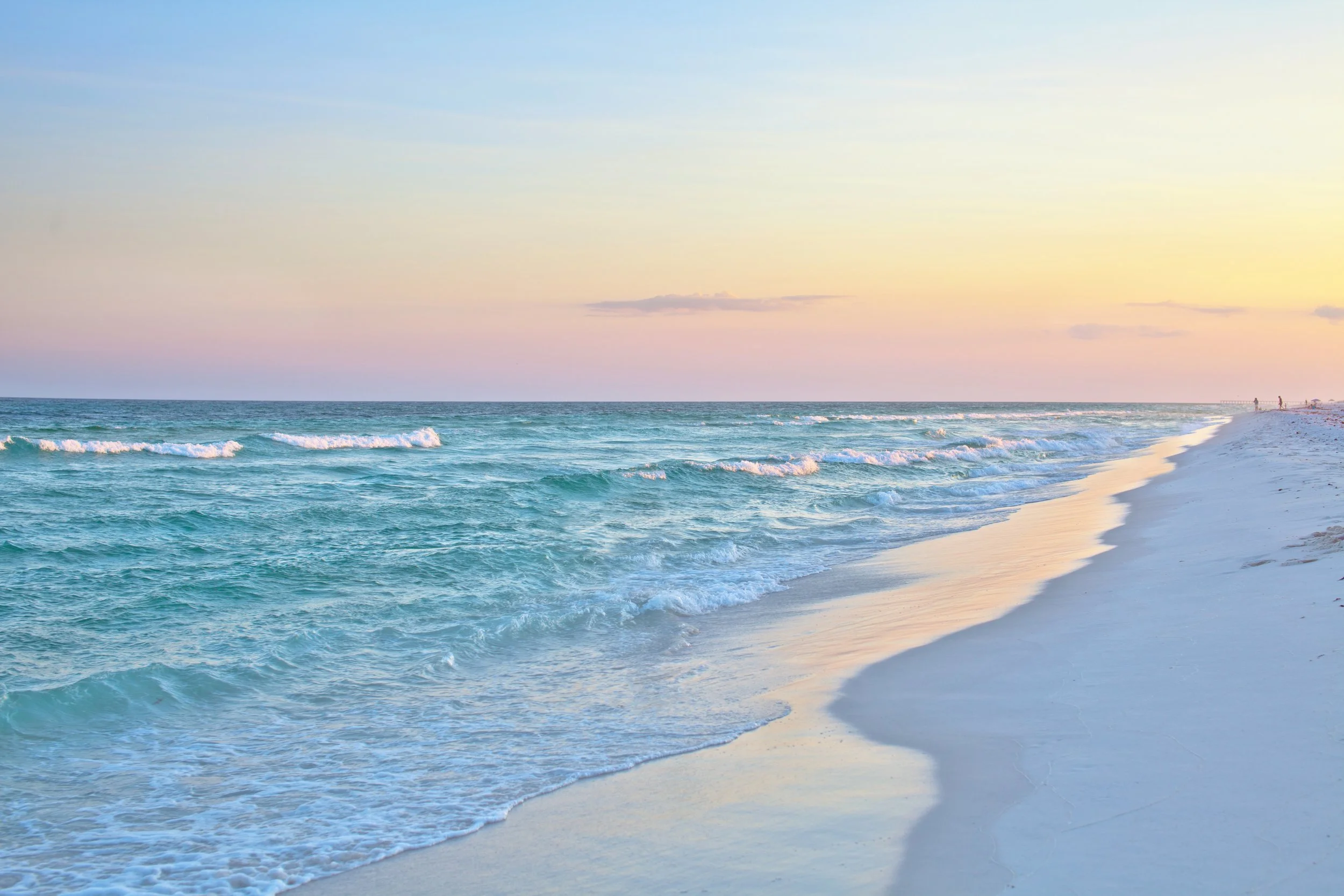 A peaceful beach at sunset with gentle waves, sandy shore, and a pastel sky with soft clouds.