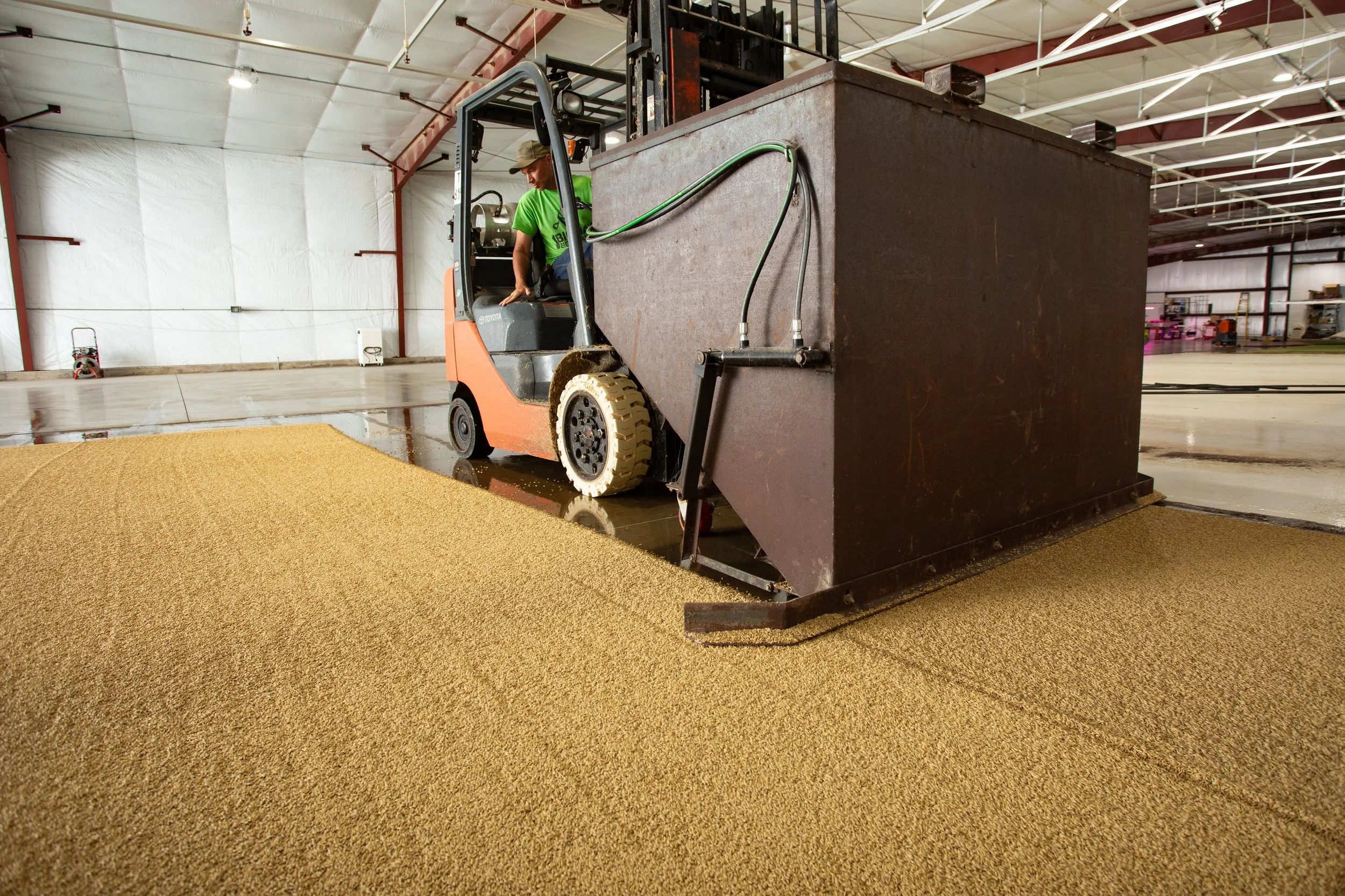 A person operating a forklift spreading barley seed for the Simon Farms Infinity Pasture System.
