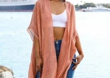 Person wearing a white crop top and pink cover-up by the water