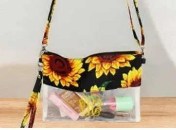 A shoulder bag with a sunflower pattern at the top and a clear plastic bottom, containing various small items inside.