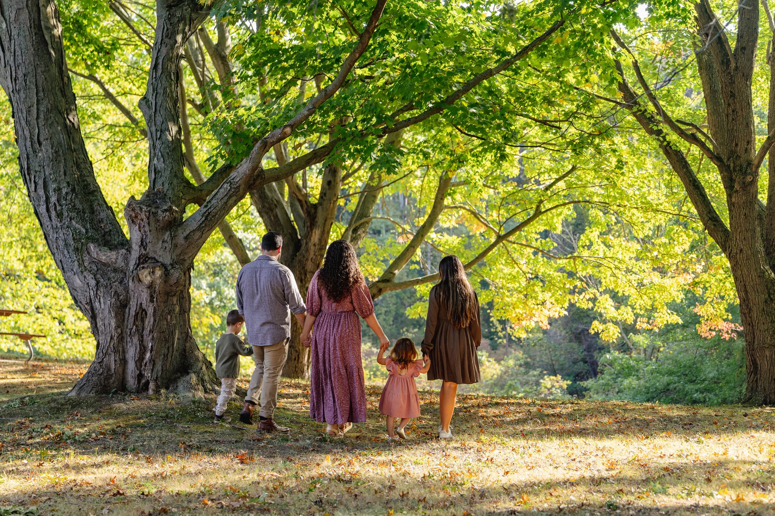 Family standing together under the trees at Webster Park during a fall morning session.