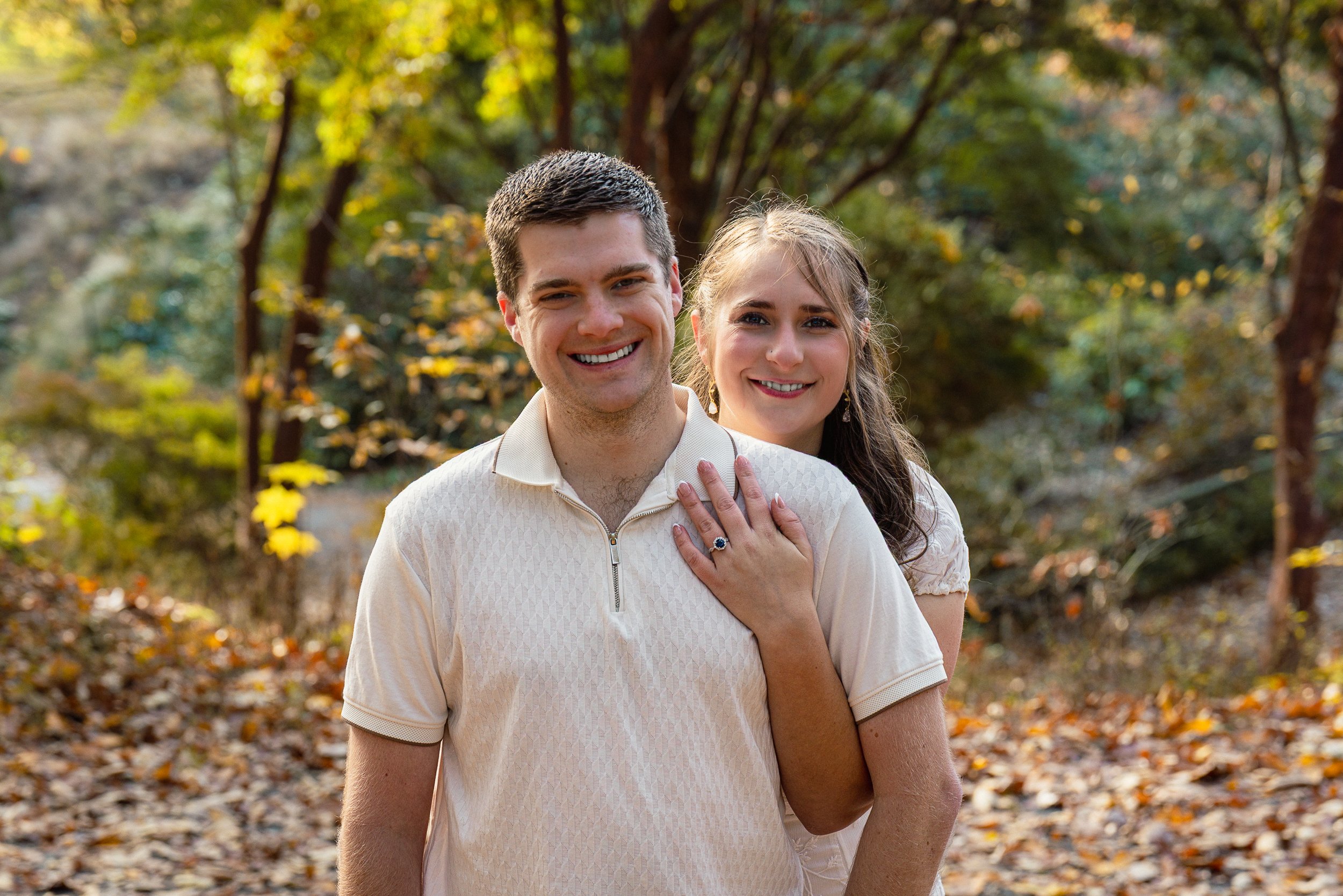 A young man and woman sitting on steps in front of a yellow door, smiling and hugging.