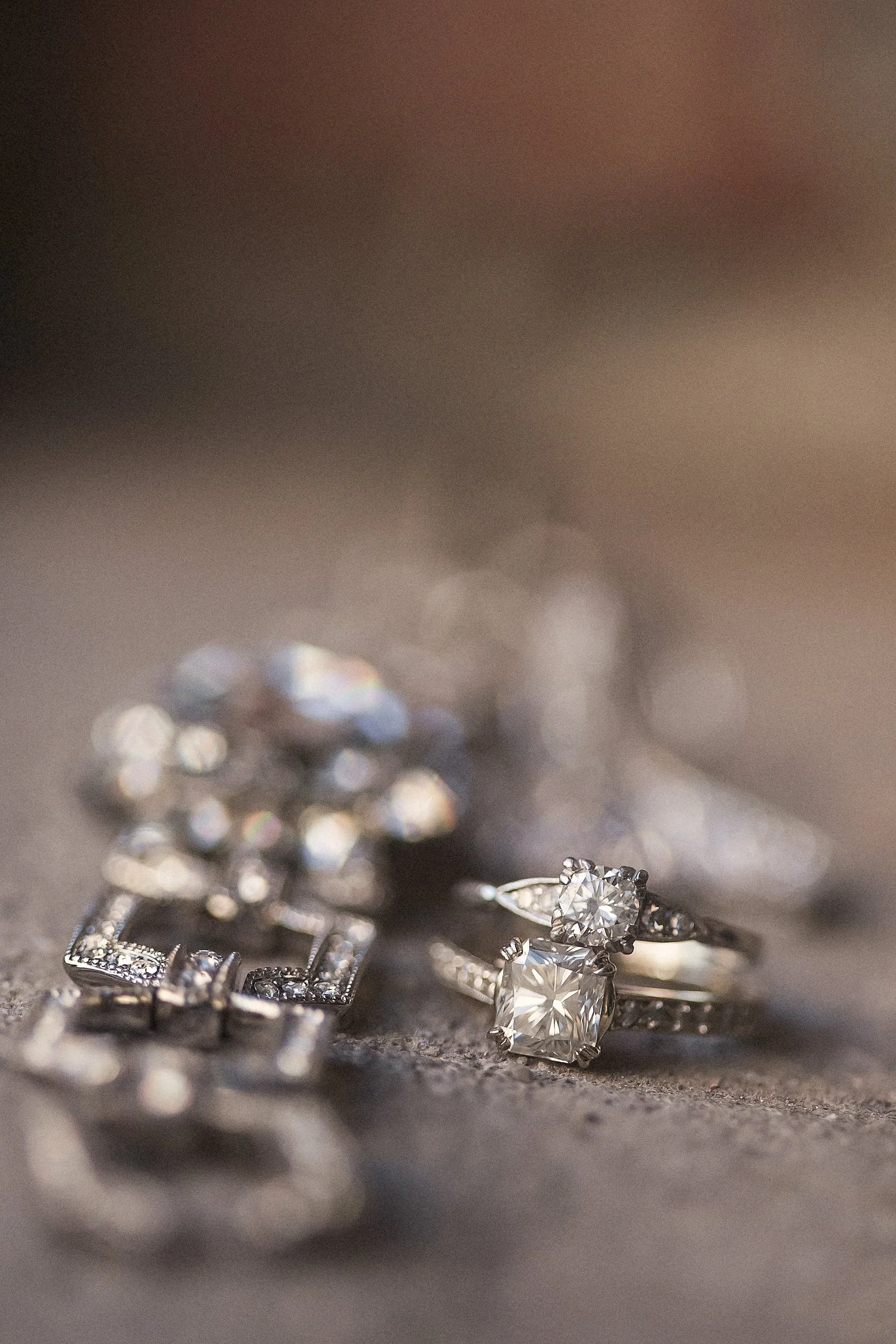 Macro image of a silver and diamond square-designed bracelet and two diamond wedding rings with white gold bands. 
