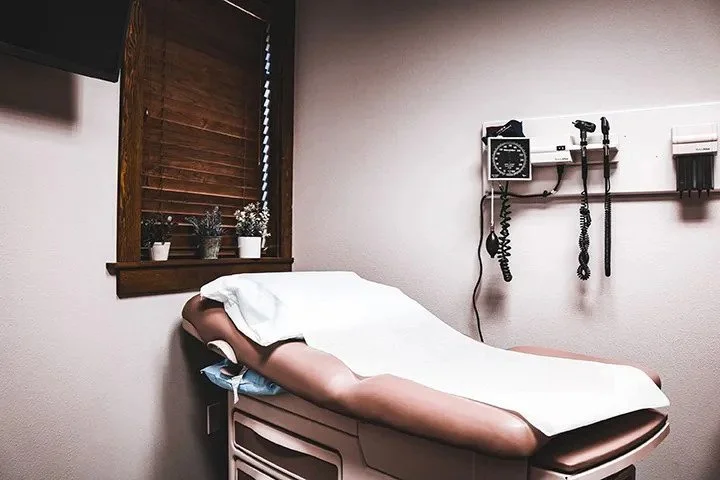Private exam room with a padded exam table and wall-mounted diagnostic equipment
