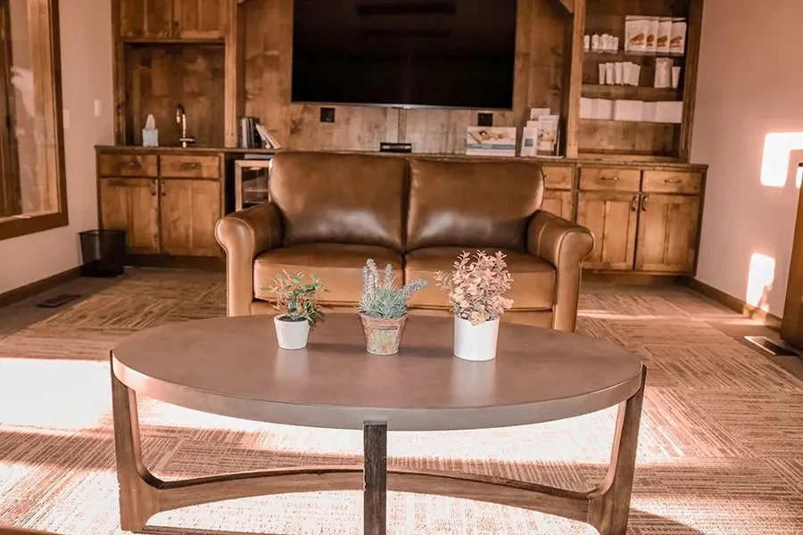Clinic waiting area with leather sofa, round coffee table and small potted plants