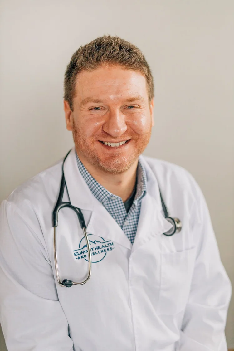 Dr. Jon Stabler smiling in a white coat with a stethoscope