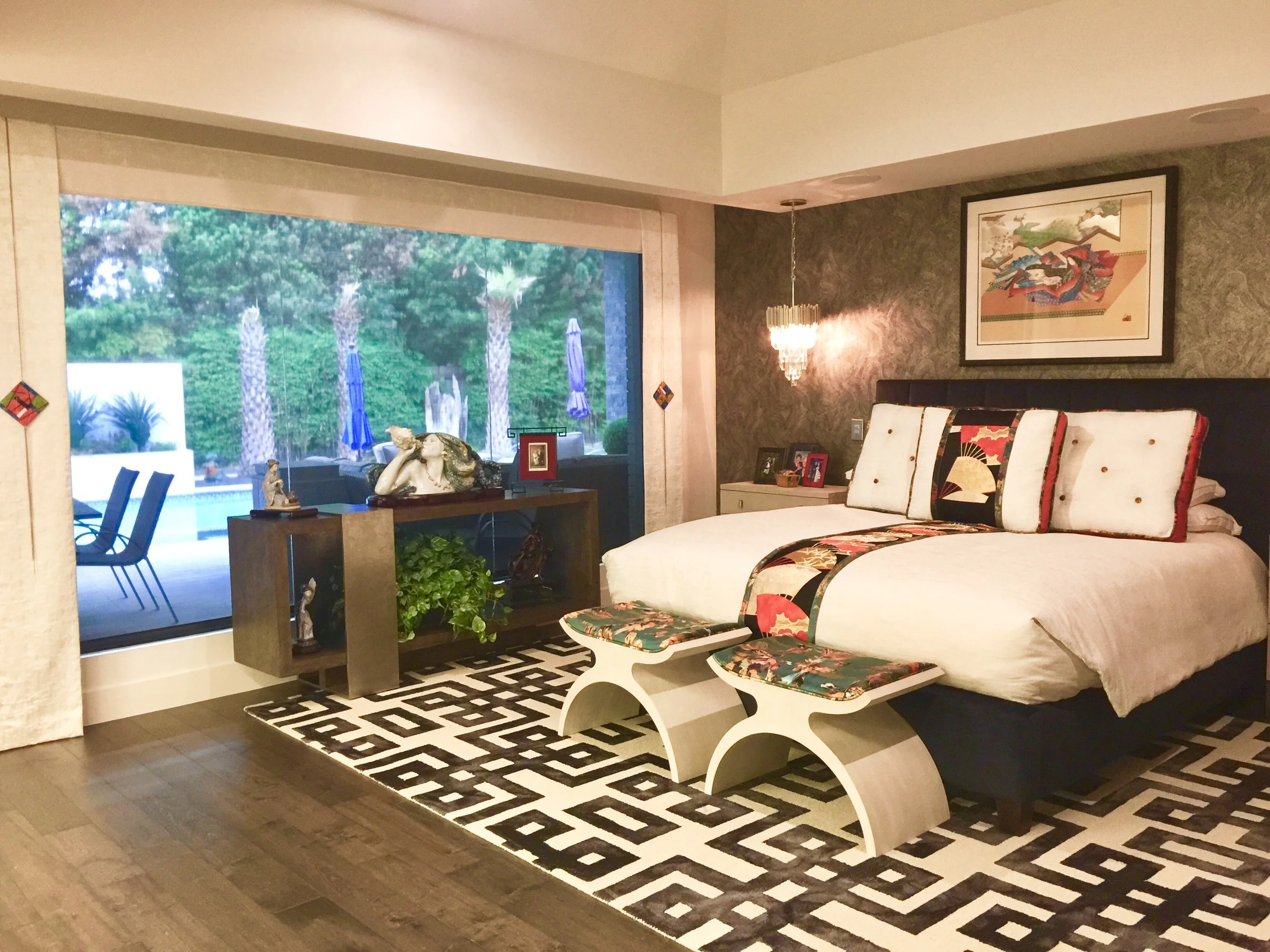 A bedroom featuring custom bedding with vintage Japanese Obi.. The wall features a textured wallpaper. There are white drape panels to the side.