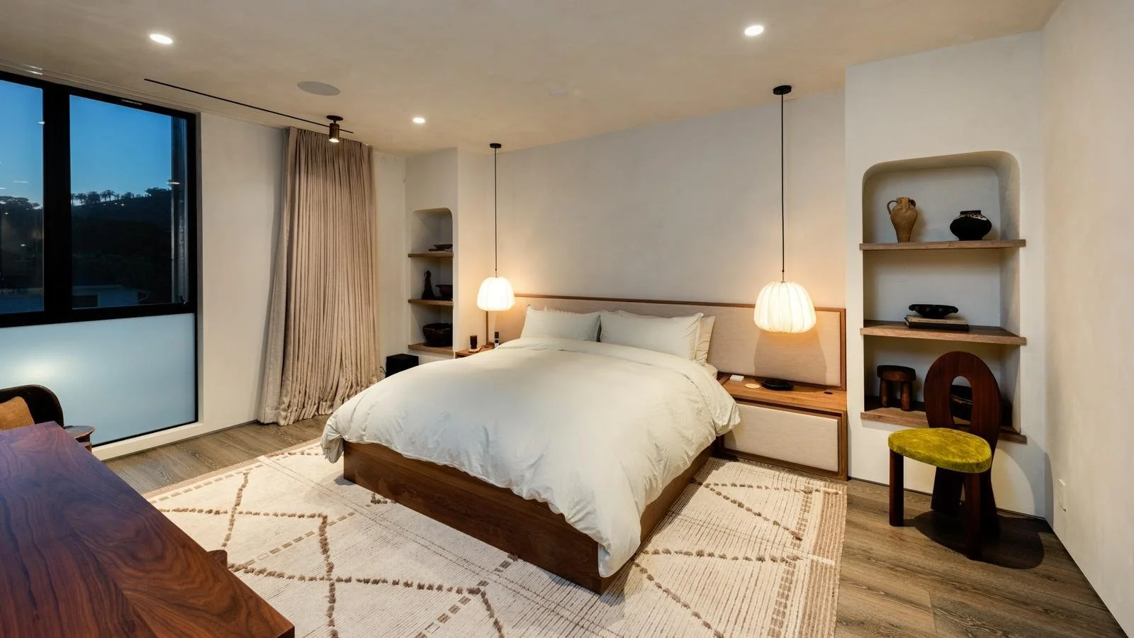 Malibu primary bedroom with custom wood bed frame and soft pendant lighting.