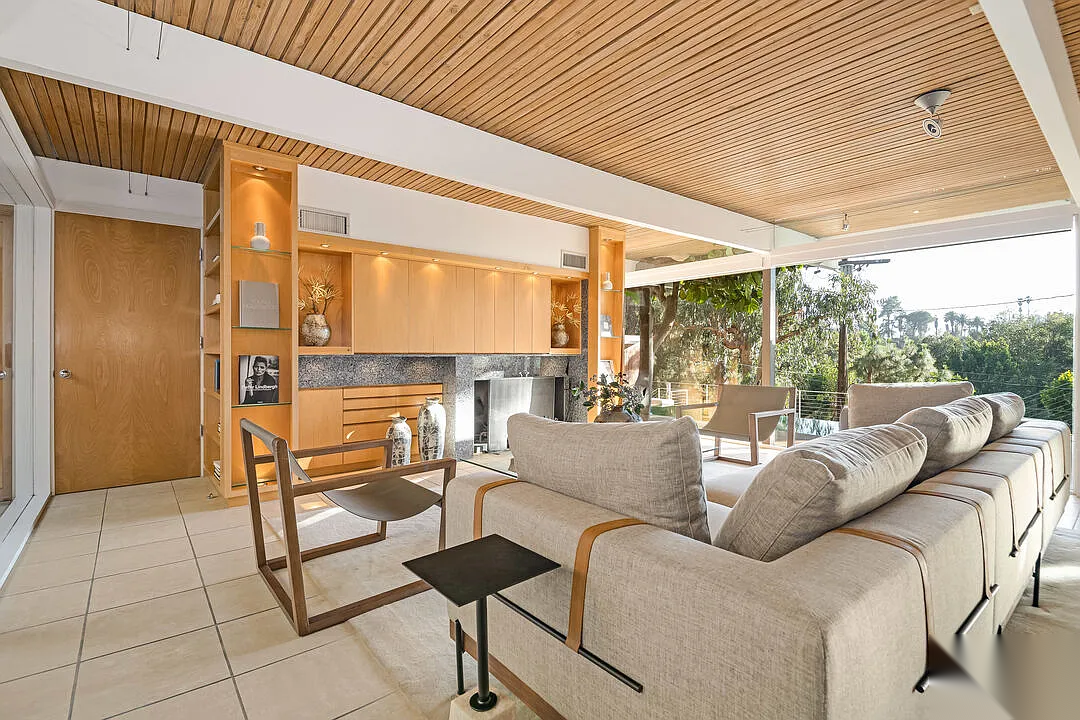 Hollywood Hills mid-century living room before renovation with original wood paneling, tiled flooring, built-in cabinetry, and limited connection to outdoor terrace