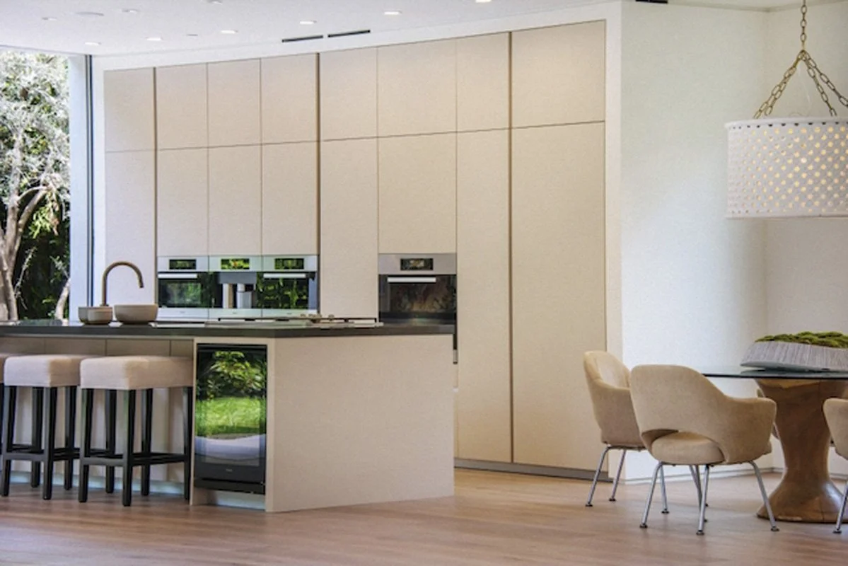 Minimalist kitchen in West Hollywood custom home with integrated cabinetry, stone island, and garden views.