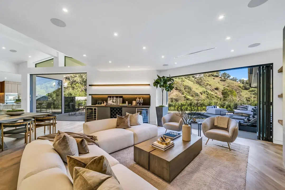 Modern Hollywood Hills living room with floor-to-ceiling glass opening to hillside views and outdoor terrace