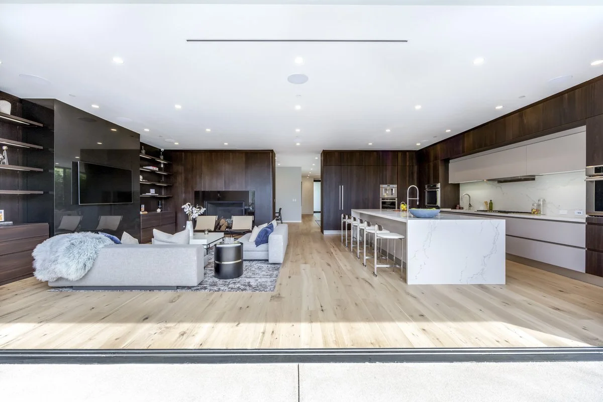Luxury West Hollywood kitchen and living space with walnut cabinetry and waterfall island